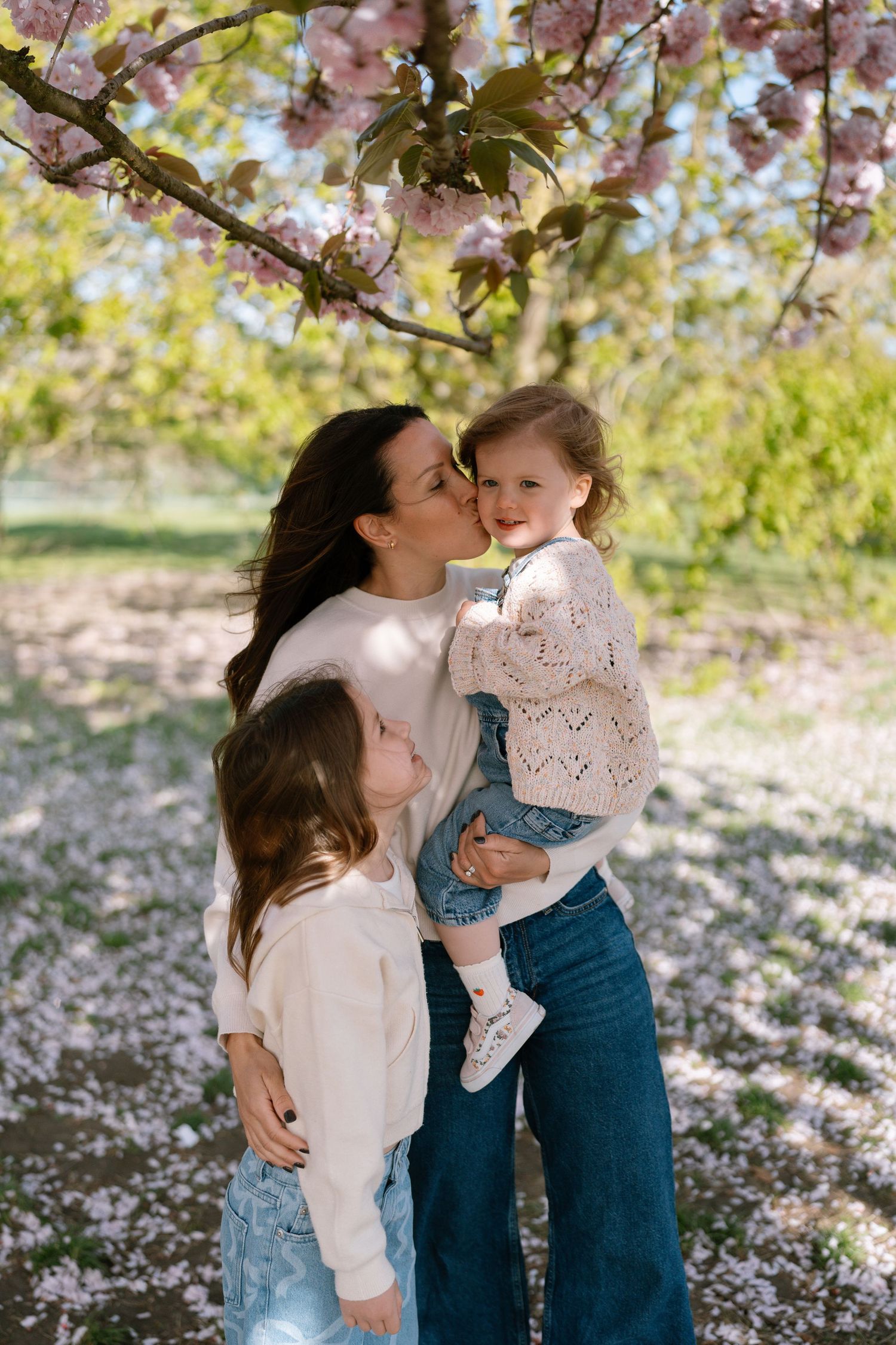 A sweet moment captured under blooming cherry blossom trees.