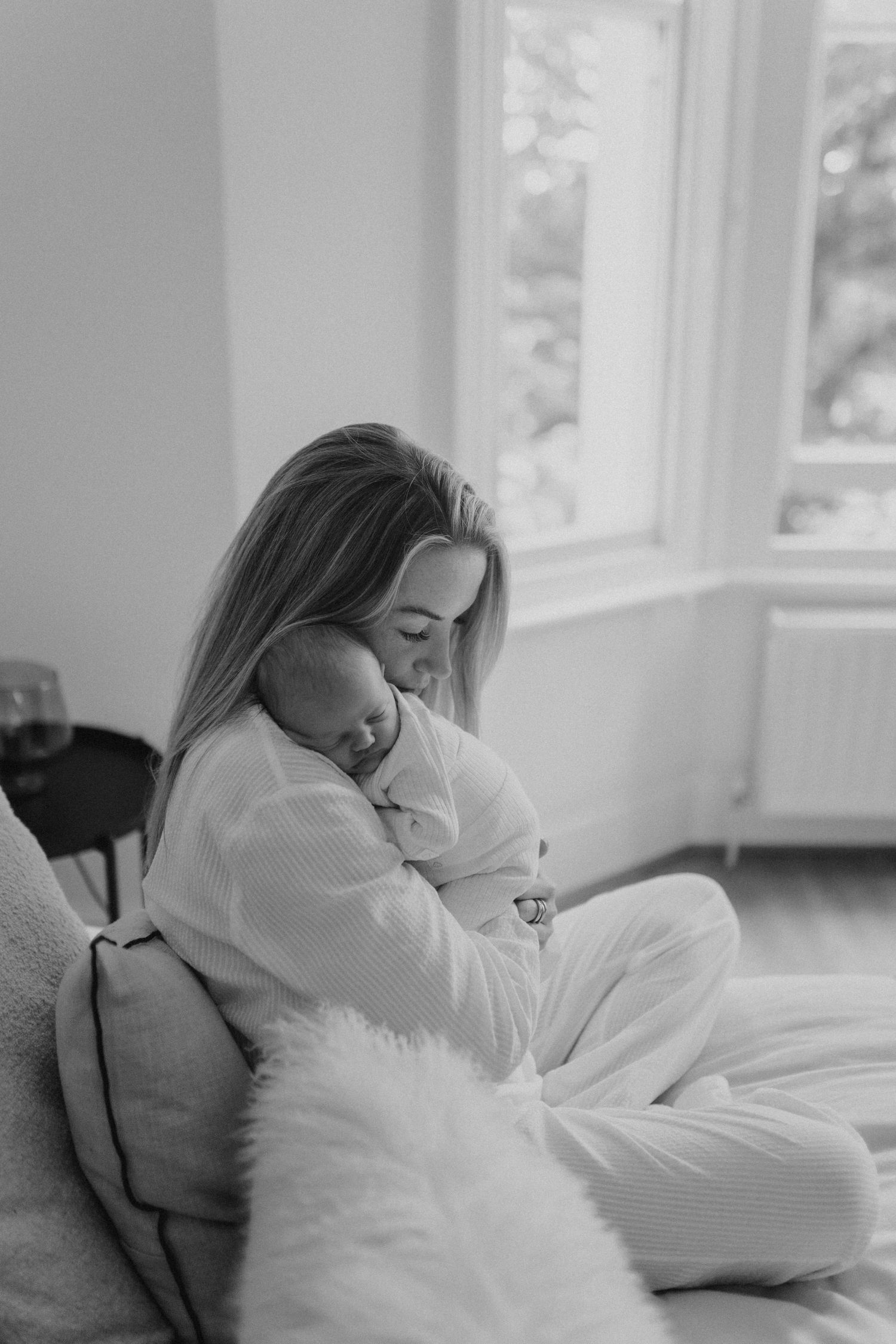 A tender moment of rest and bonding in a bright, airy bedroom.