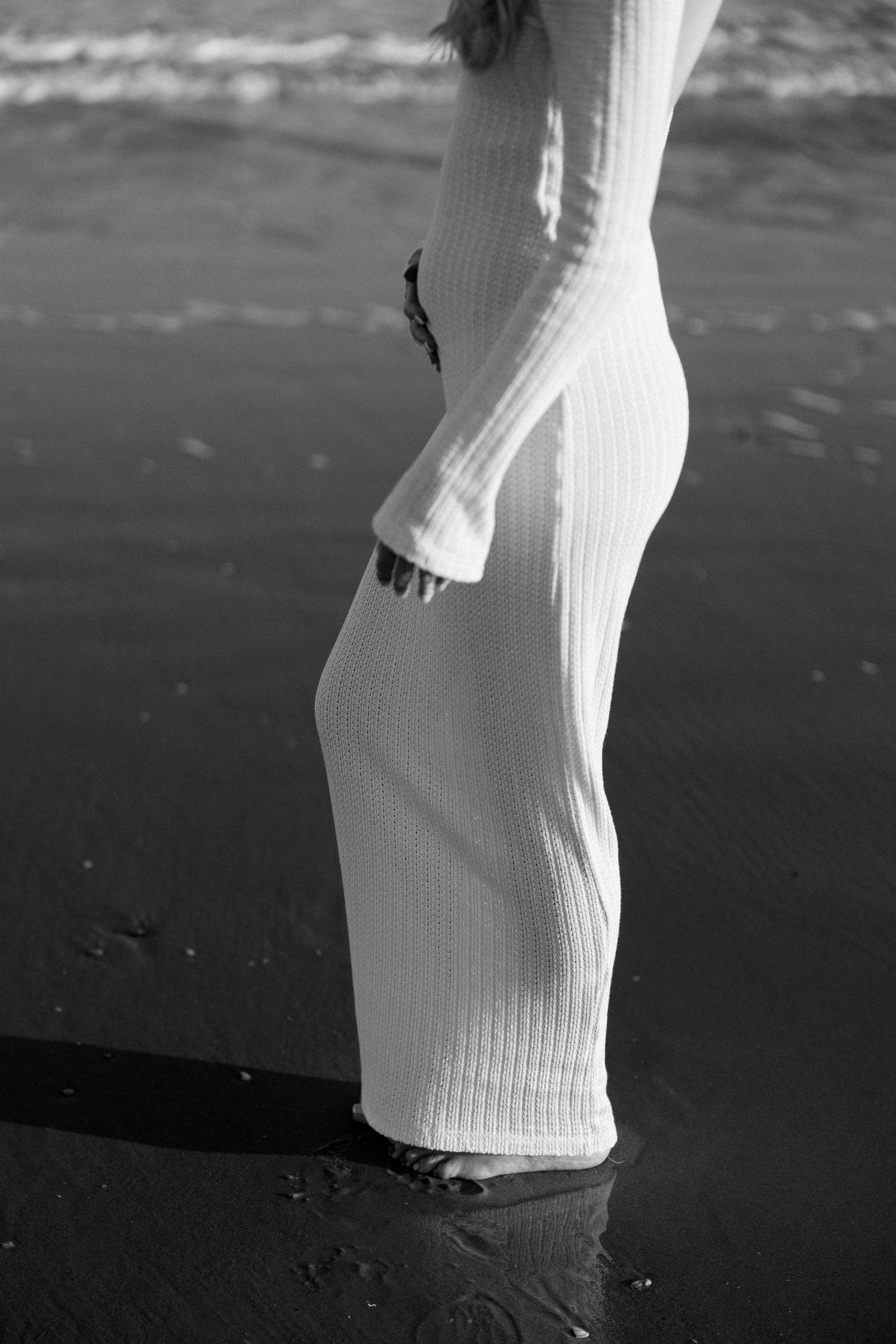 Close-up of white knit fabric against a dark sandy beach background.