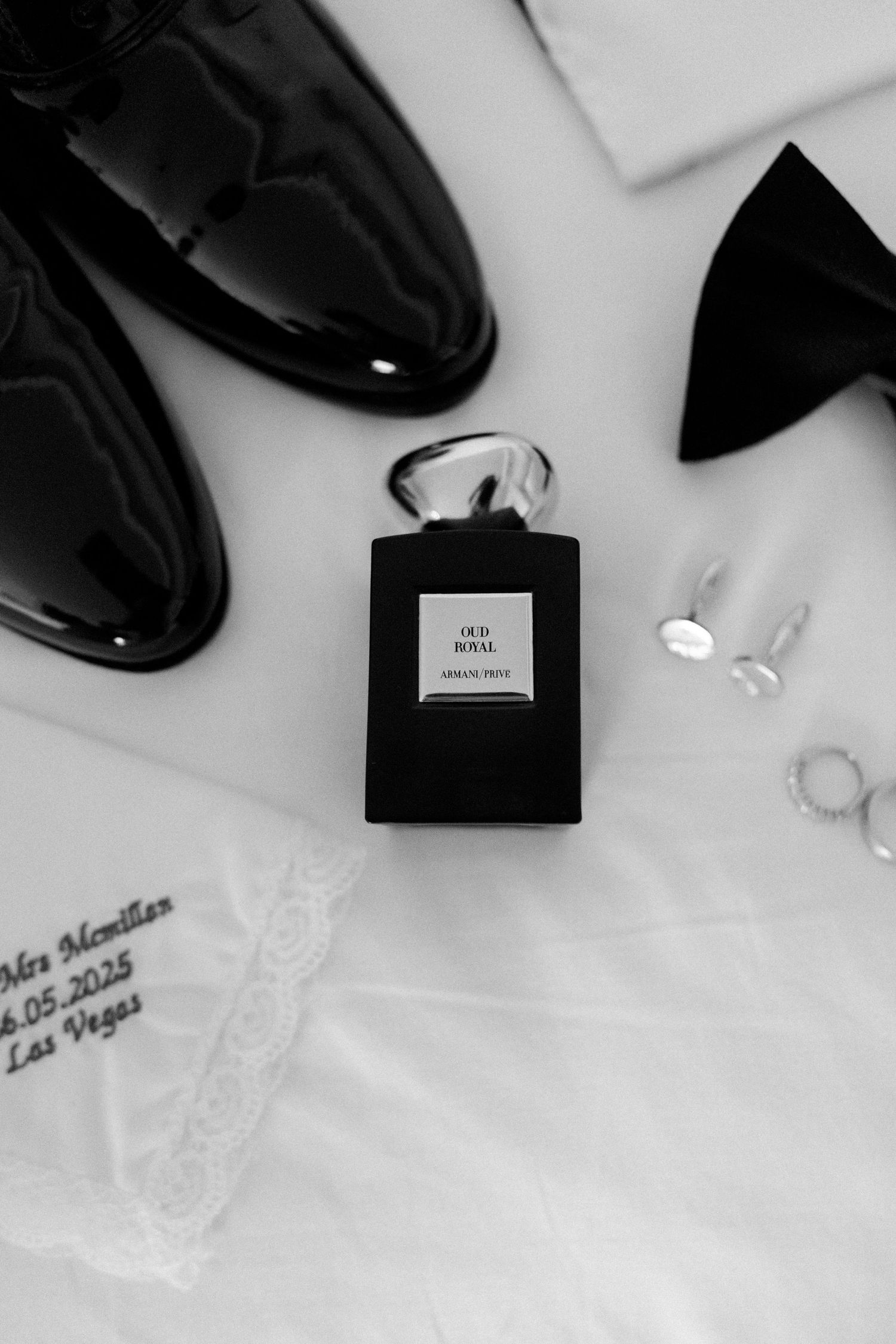 Wedding accessories including dress shoes, rings, and bow tie arranged in black and white.