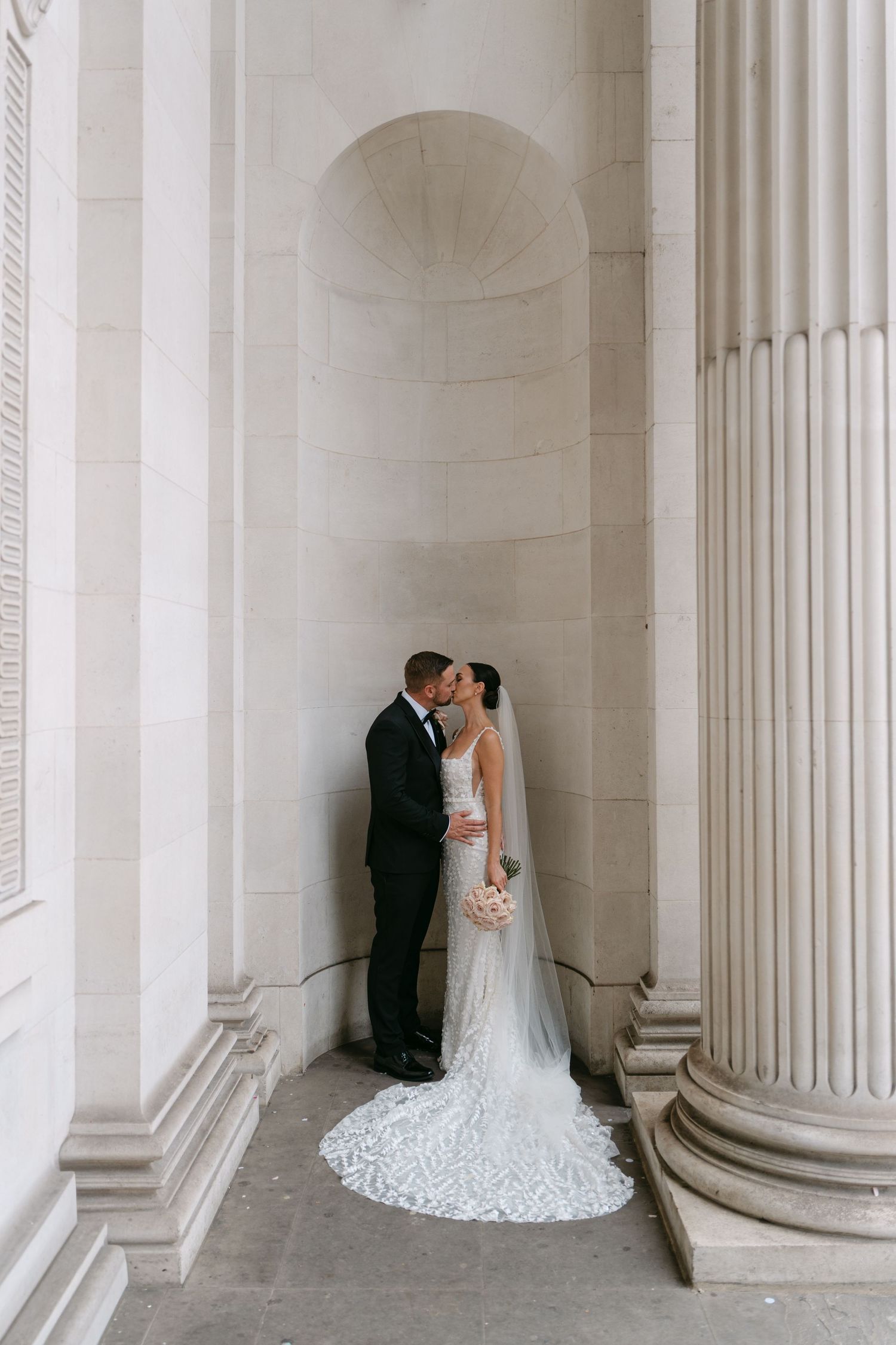 Romantic wedding portraits captured between elegant white stone columns.