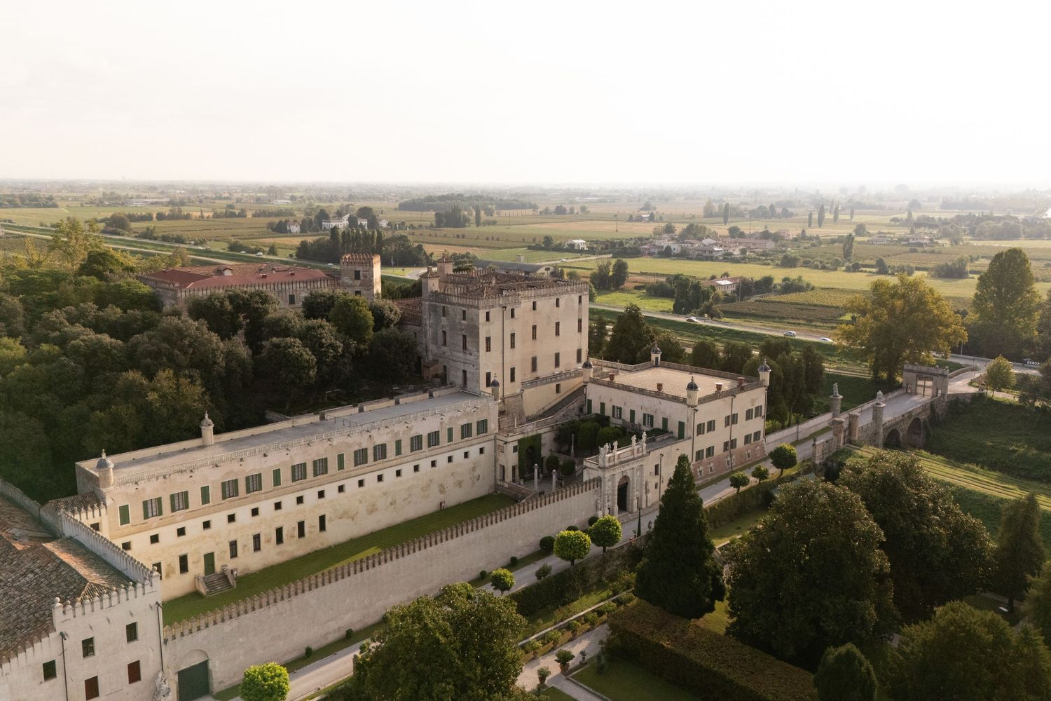 Aerial view of a majestic villa complex with formal gardens and architecture.