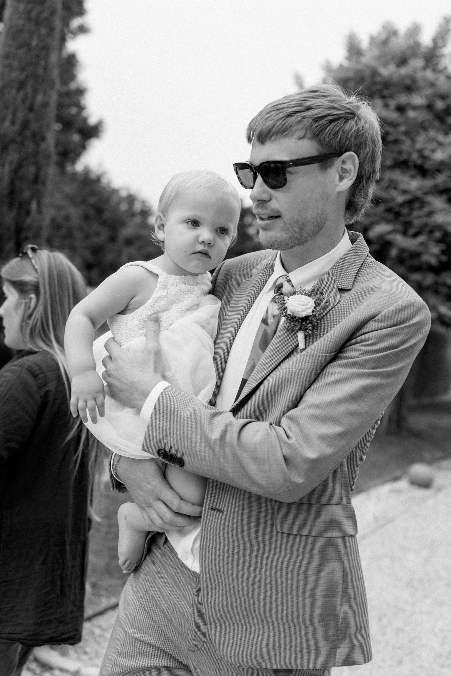 Black and white photo of person holding child at outdoor wedding venue.