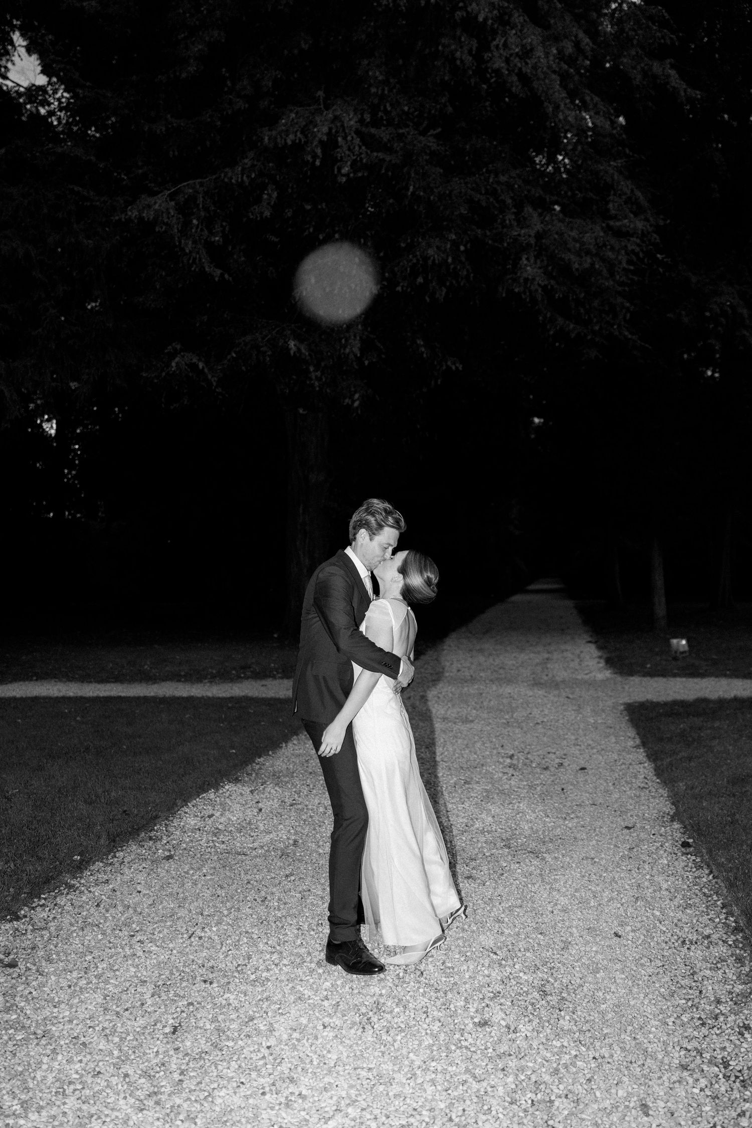 Couple shares intimate dance moment on gravel path at dusk.