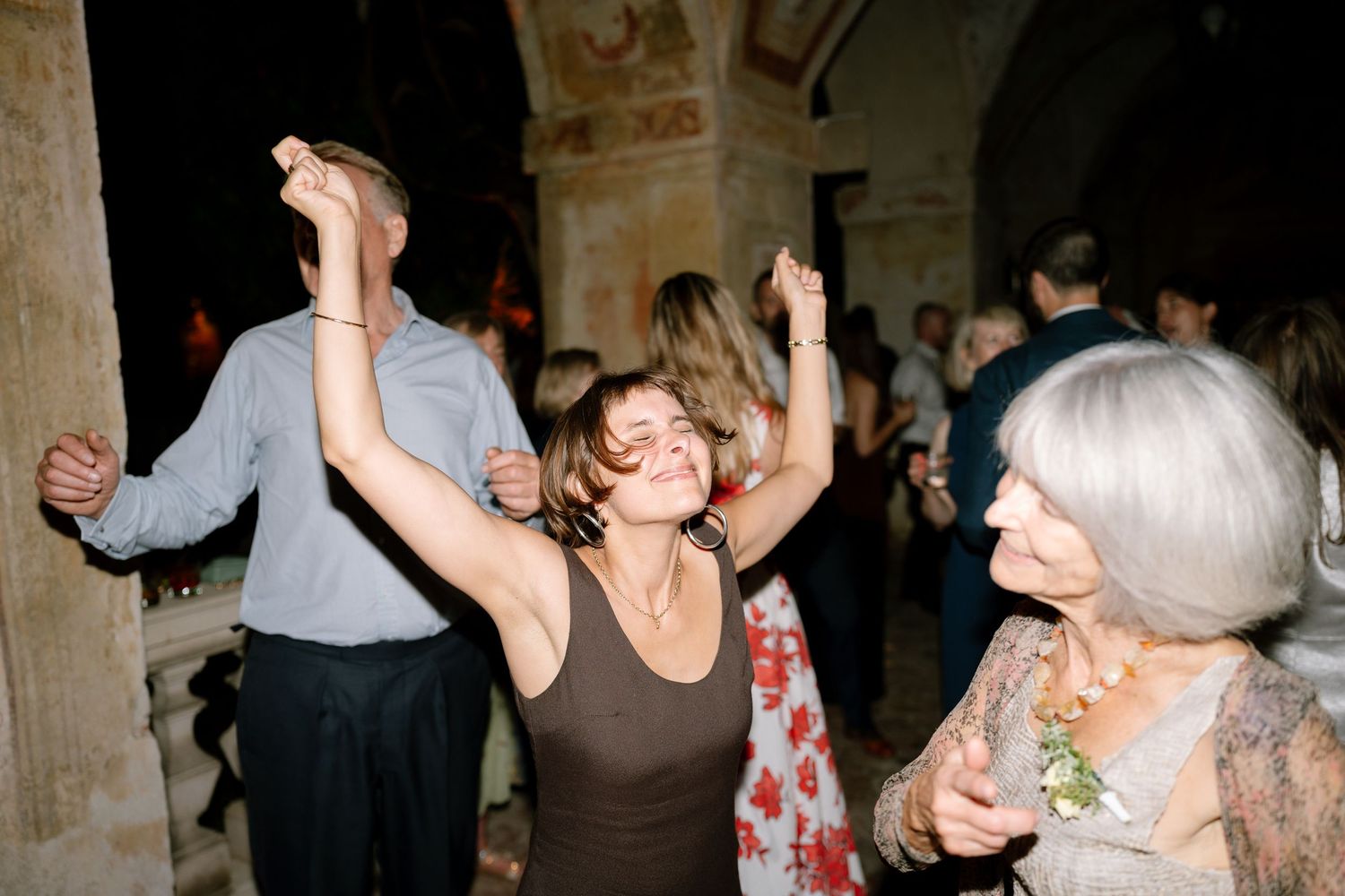 Crowd of party guests dancing and celebrating in a dimly lit venue.