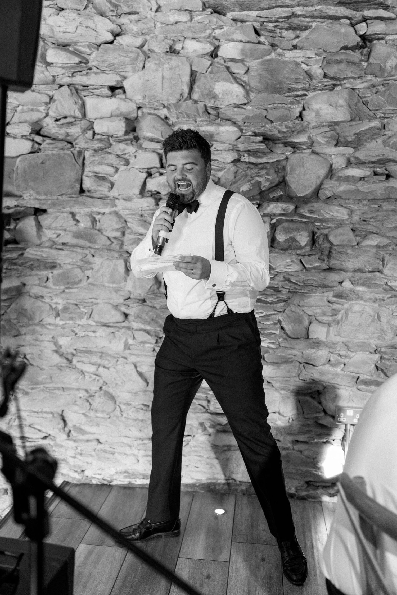 A sequence of dynamic dance moves captured in black and white against a rustic stone wall background.