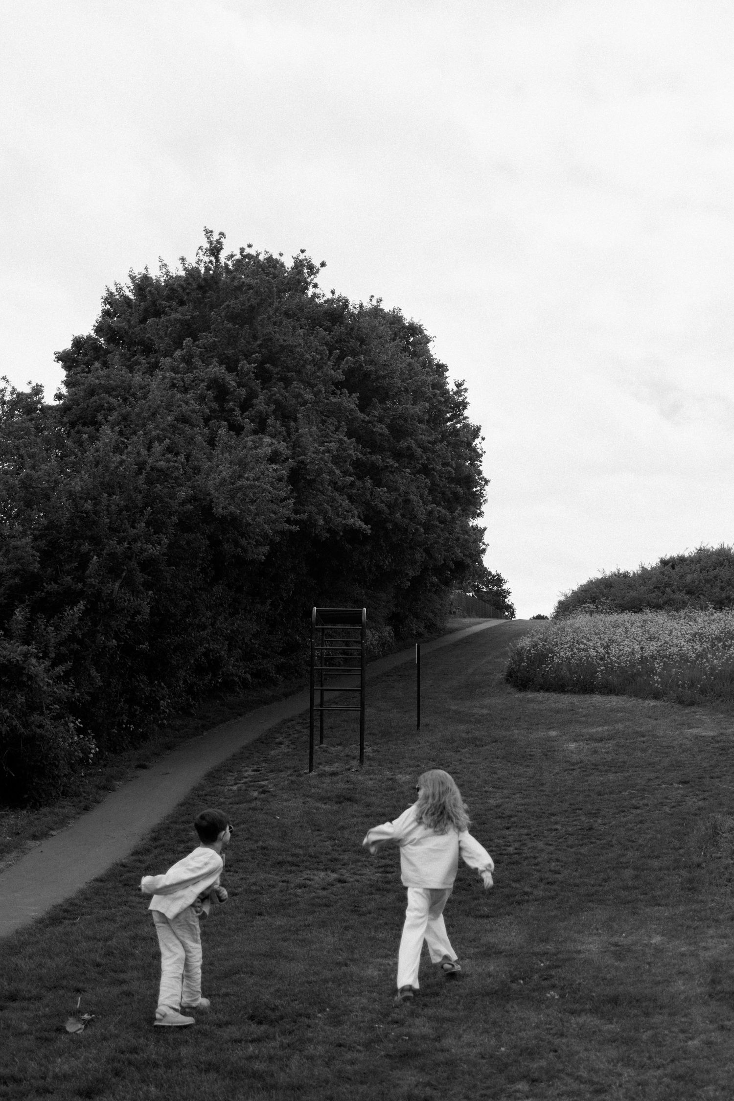 Black and white scene of people in white clothing running across a grassy hillside.