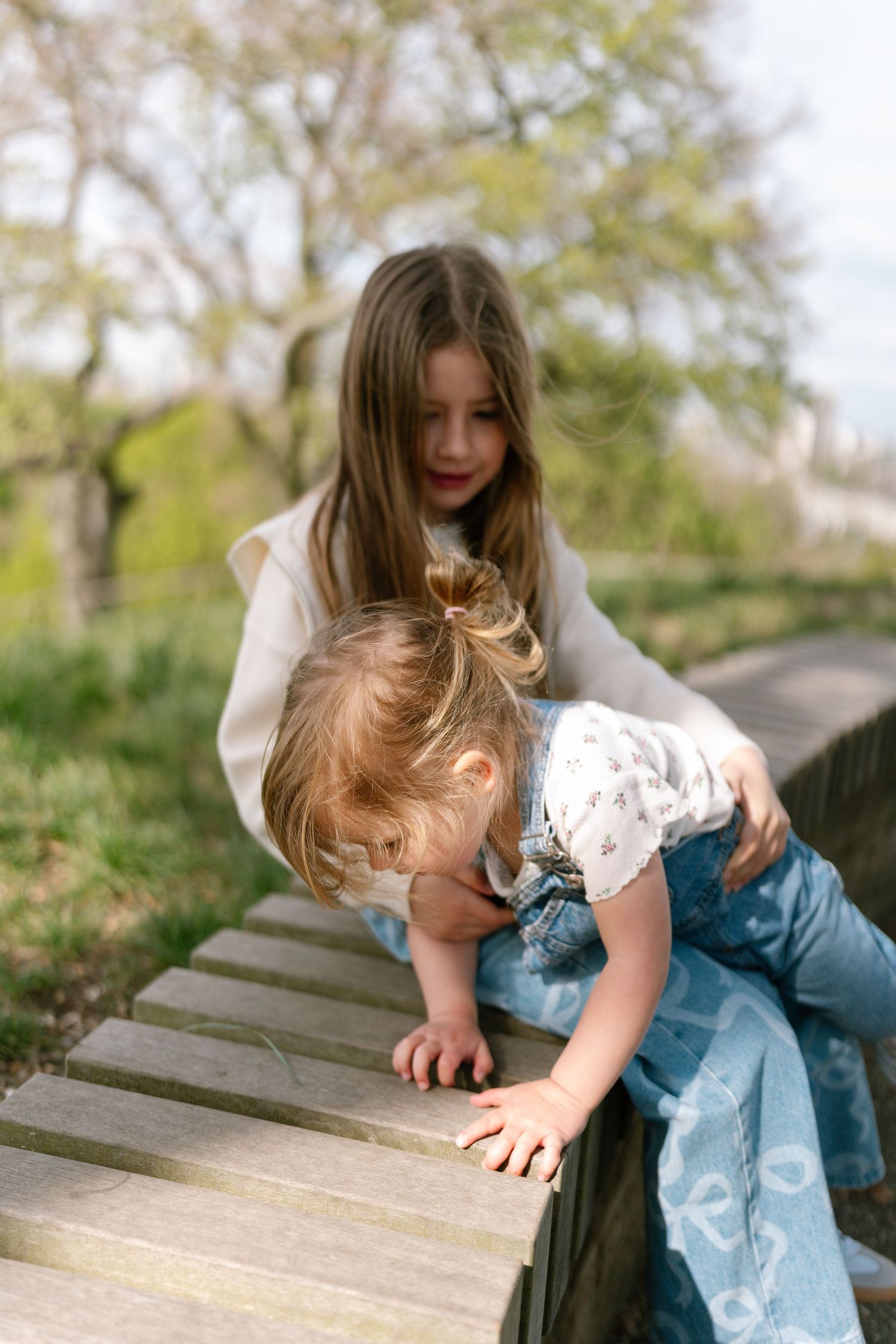 Two people lean forward on wooden planks in a park setting.