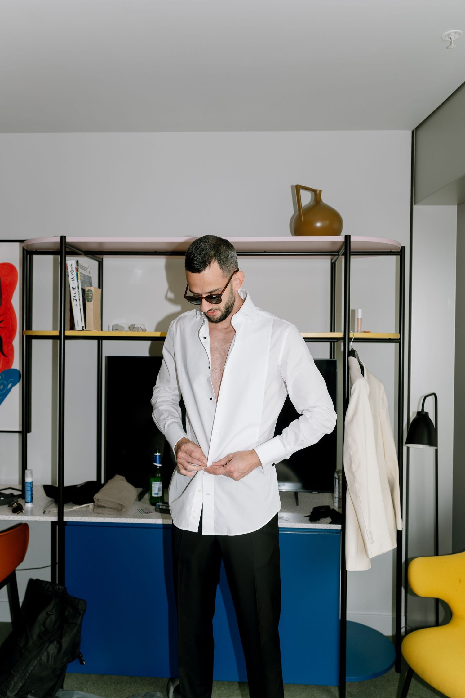 Person buttoning up white dress shirt while getting ready.
