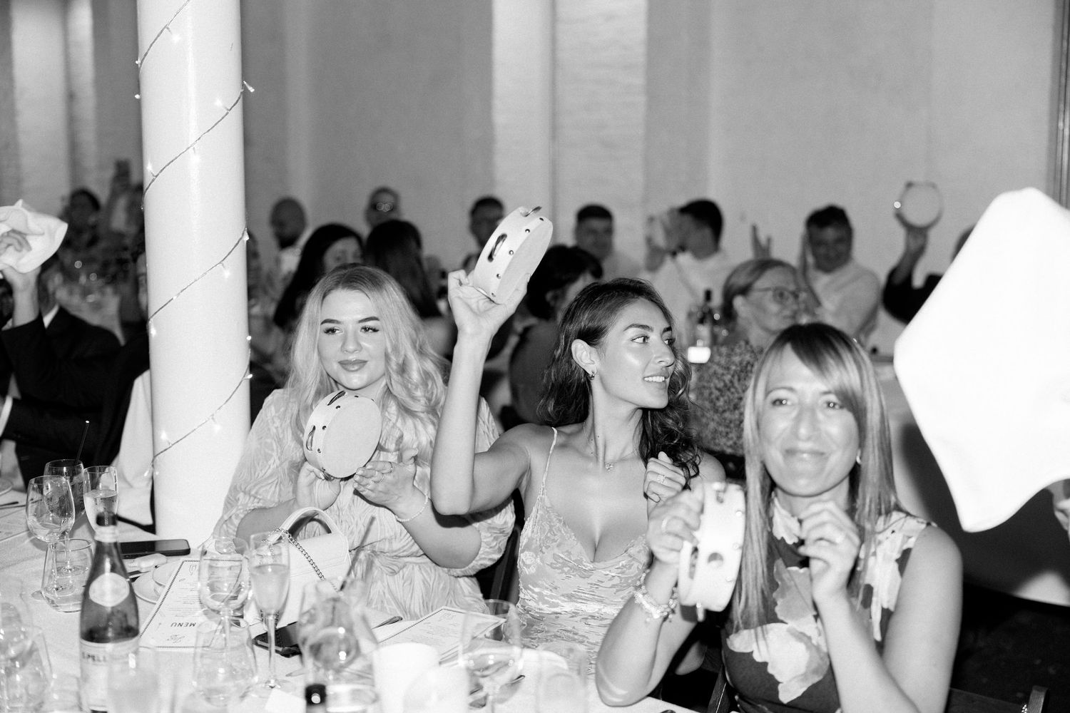 Wedding reception guests celebrating and dining at elegantly set tables.