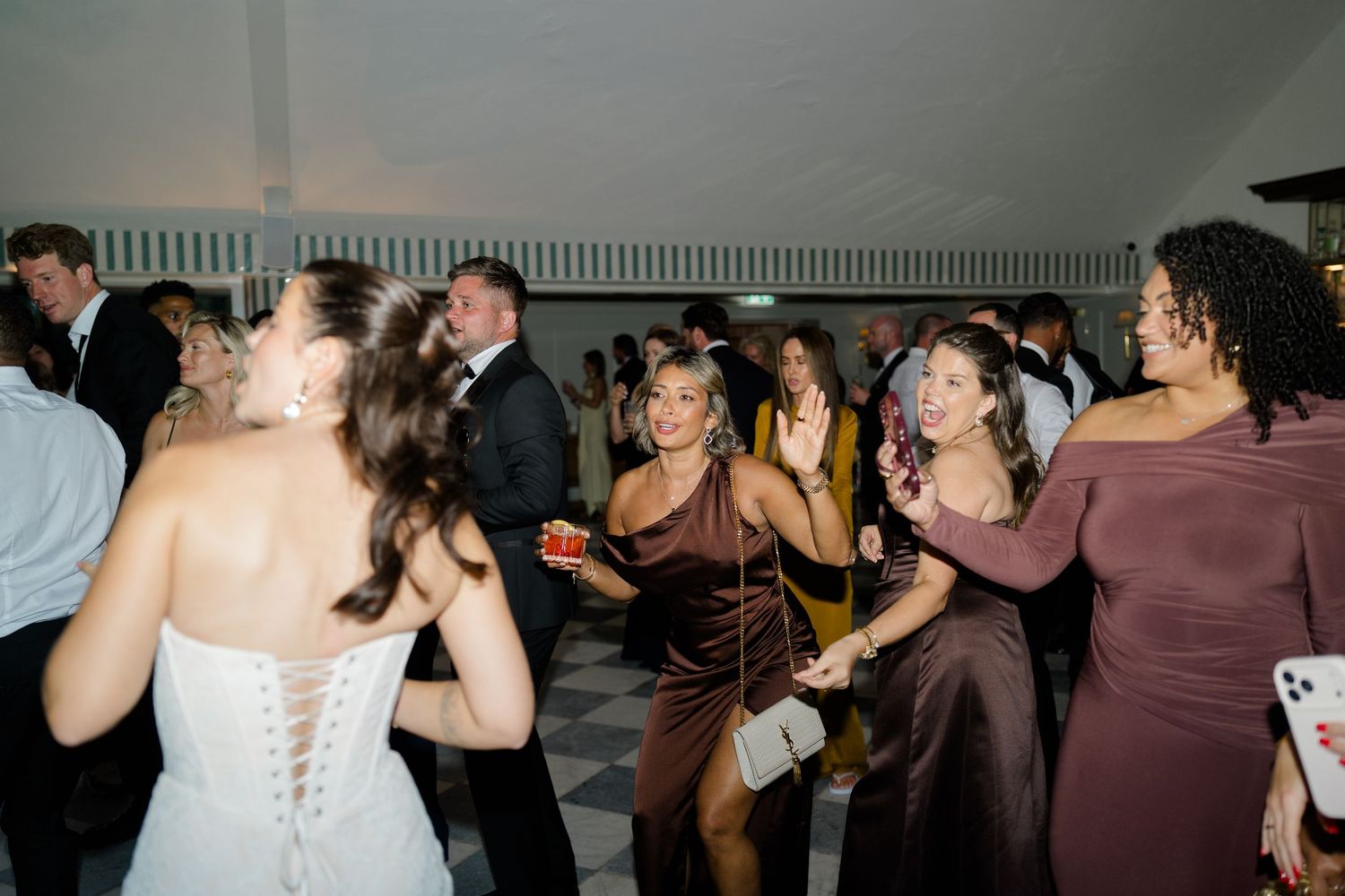 Energetic wedding reception dance floor with guests in formal attire dancing and celebrating together.
