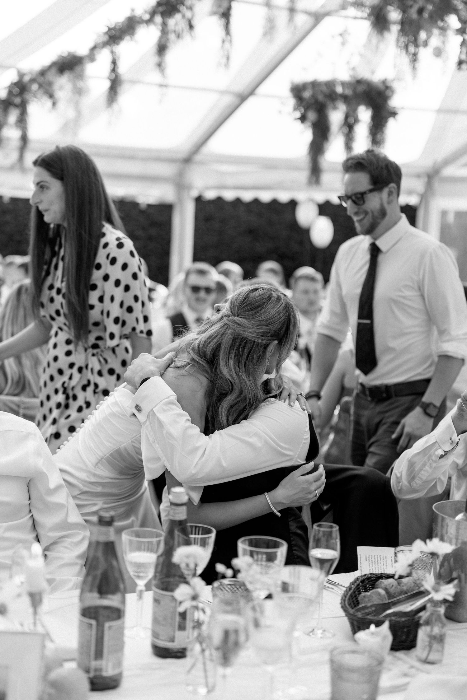 Wedding reception guests enjoying a lively moment under a tent with polka dot and white attire.