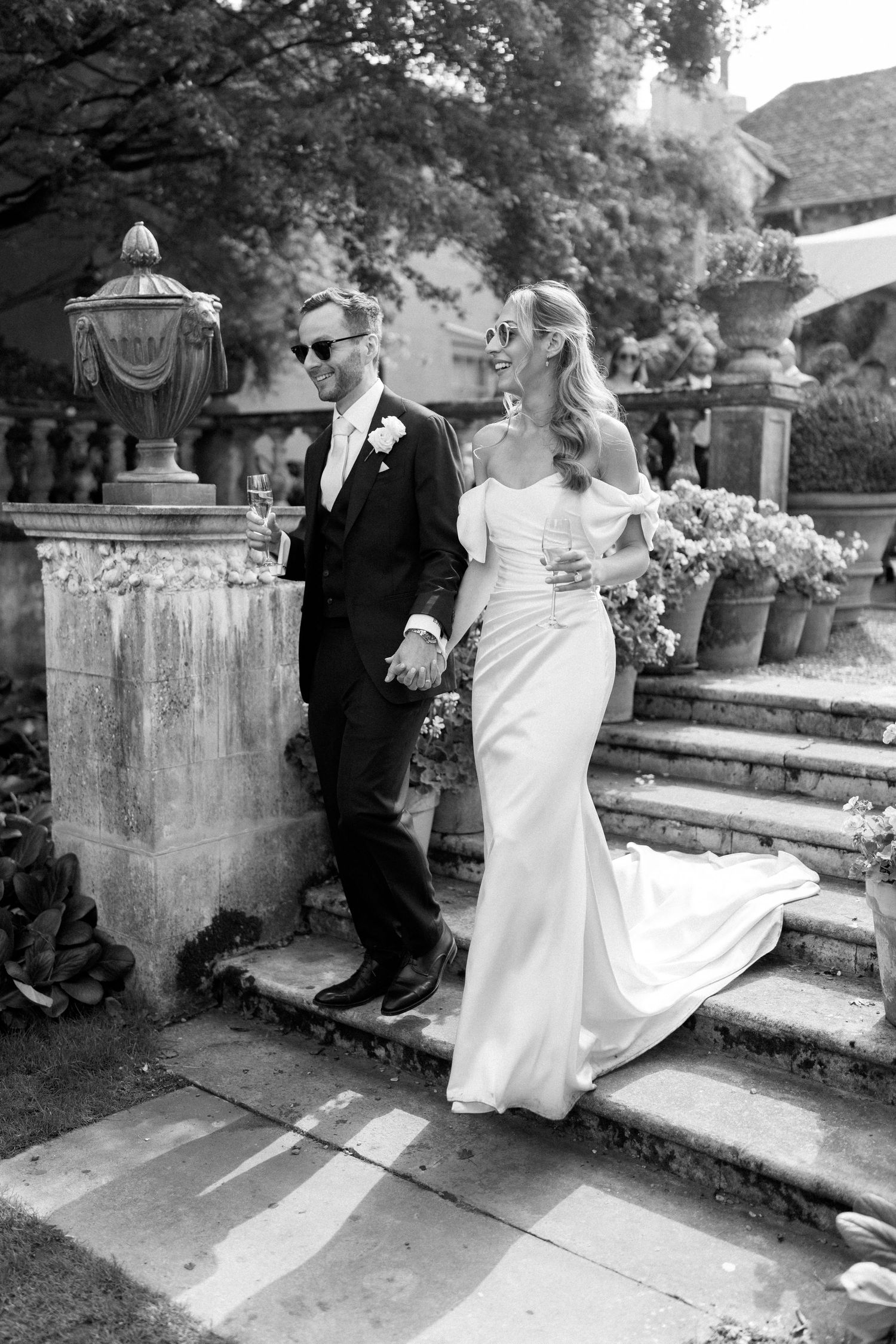 Wedding couple sitting on stone steps in a garden setting.