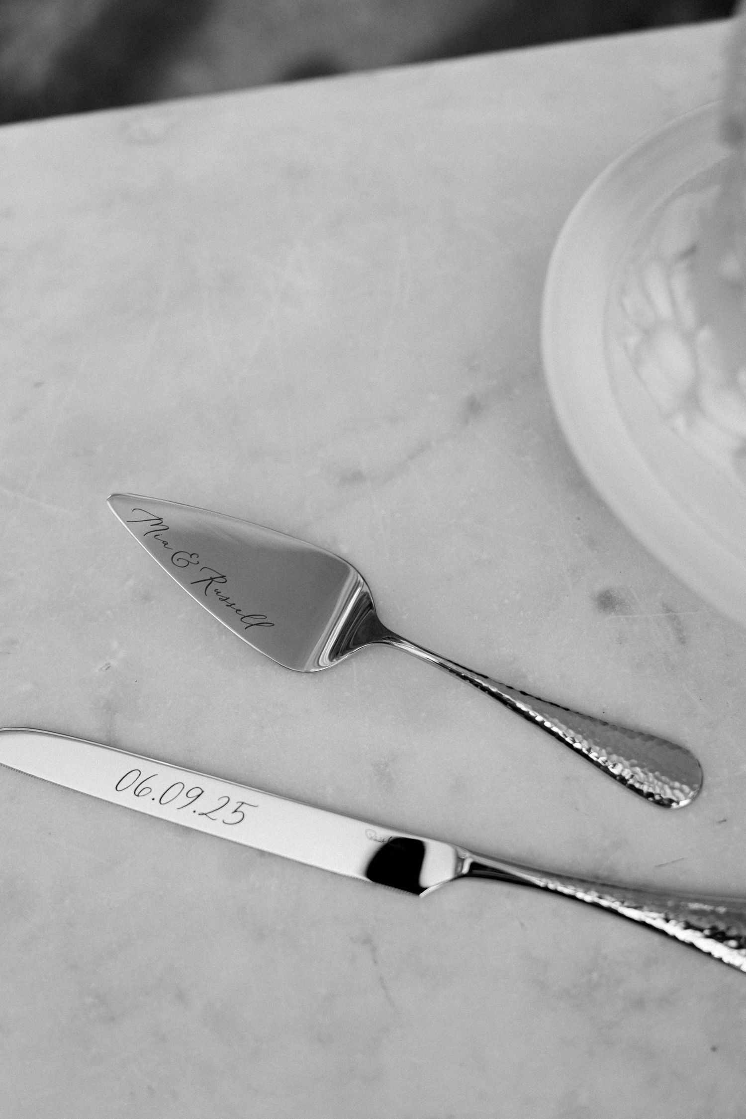 Black and white photo of a decorative cake knife on marble surface.