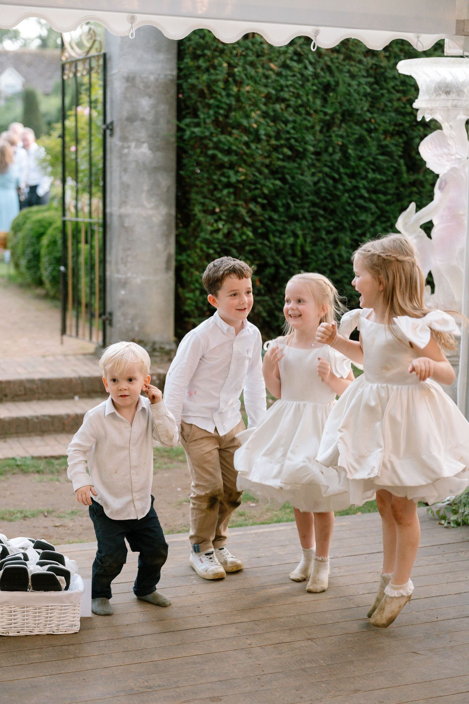 Children in formal attire playing and dancing on a garden terrace.