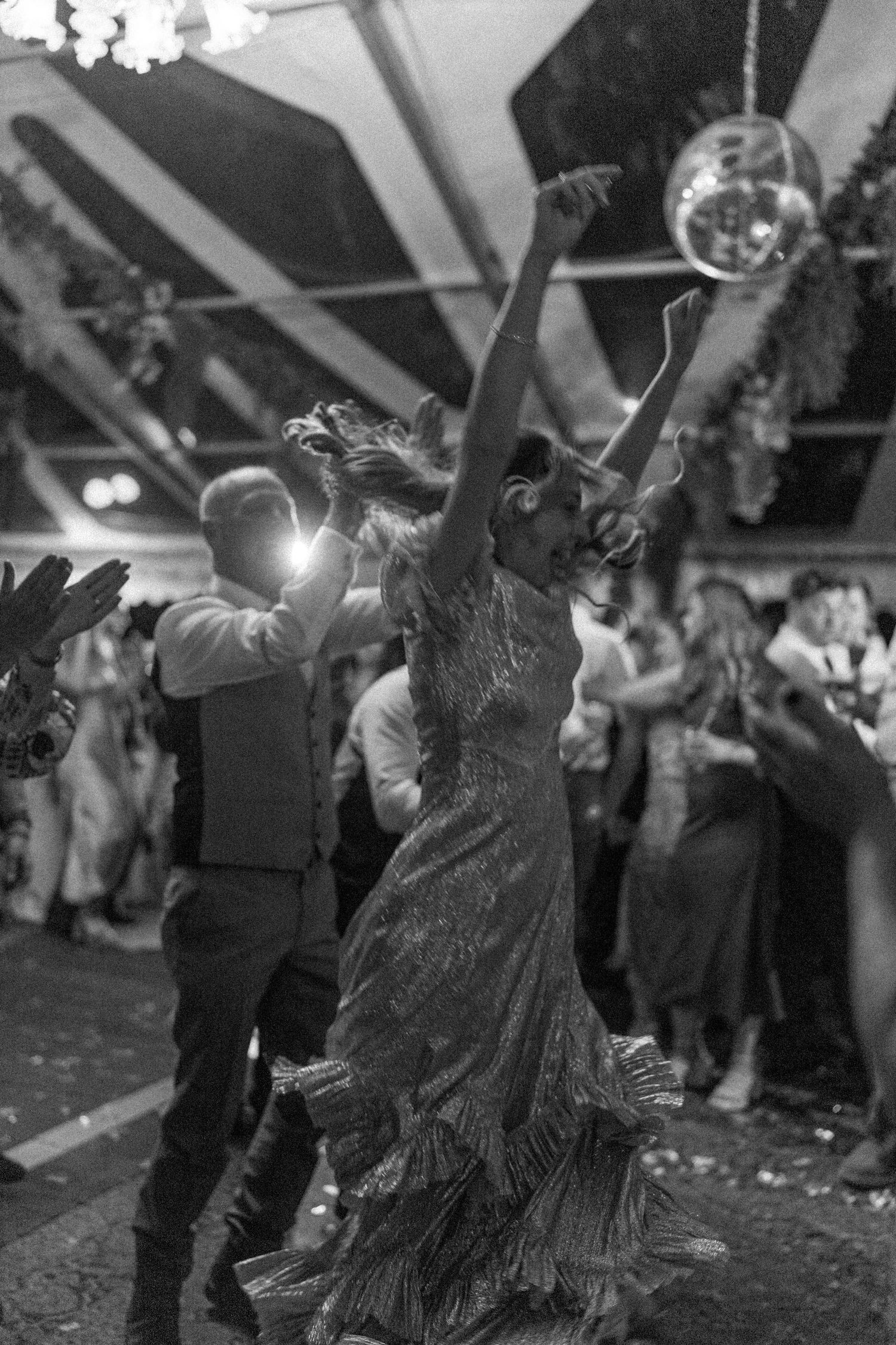 Couples dancing energetically at an indoor celebration with festive decorations.