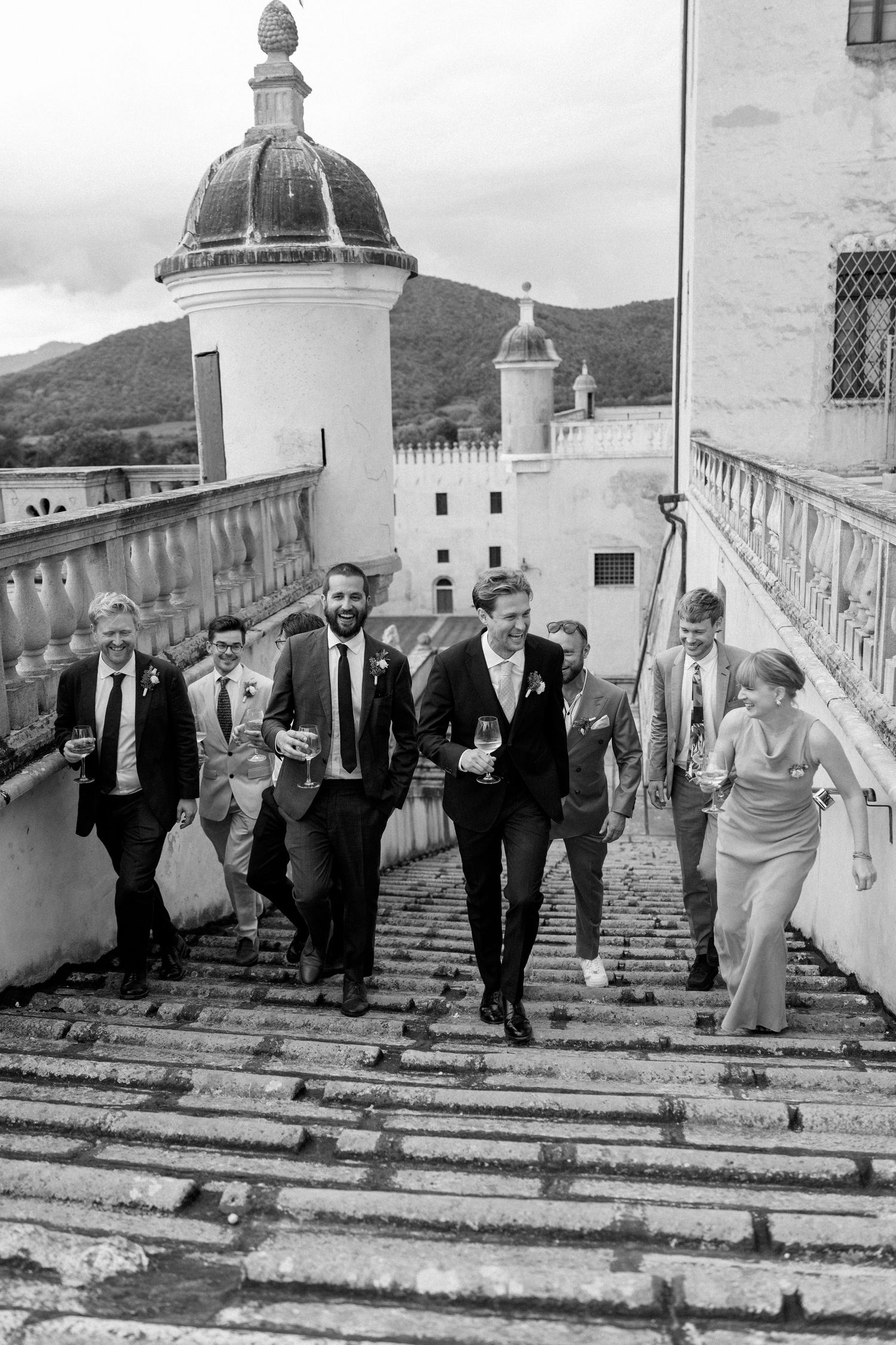 A group walking up stone steps of a building with domed towers and mountain views.