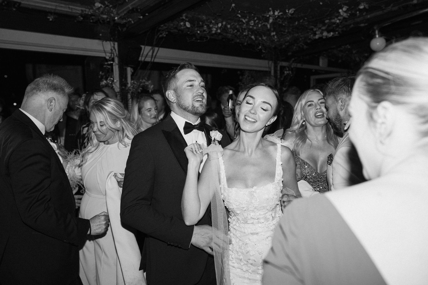 Wedding guests enjoy themselves on a crowded dance floor during the reception celebration.