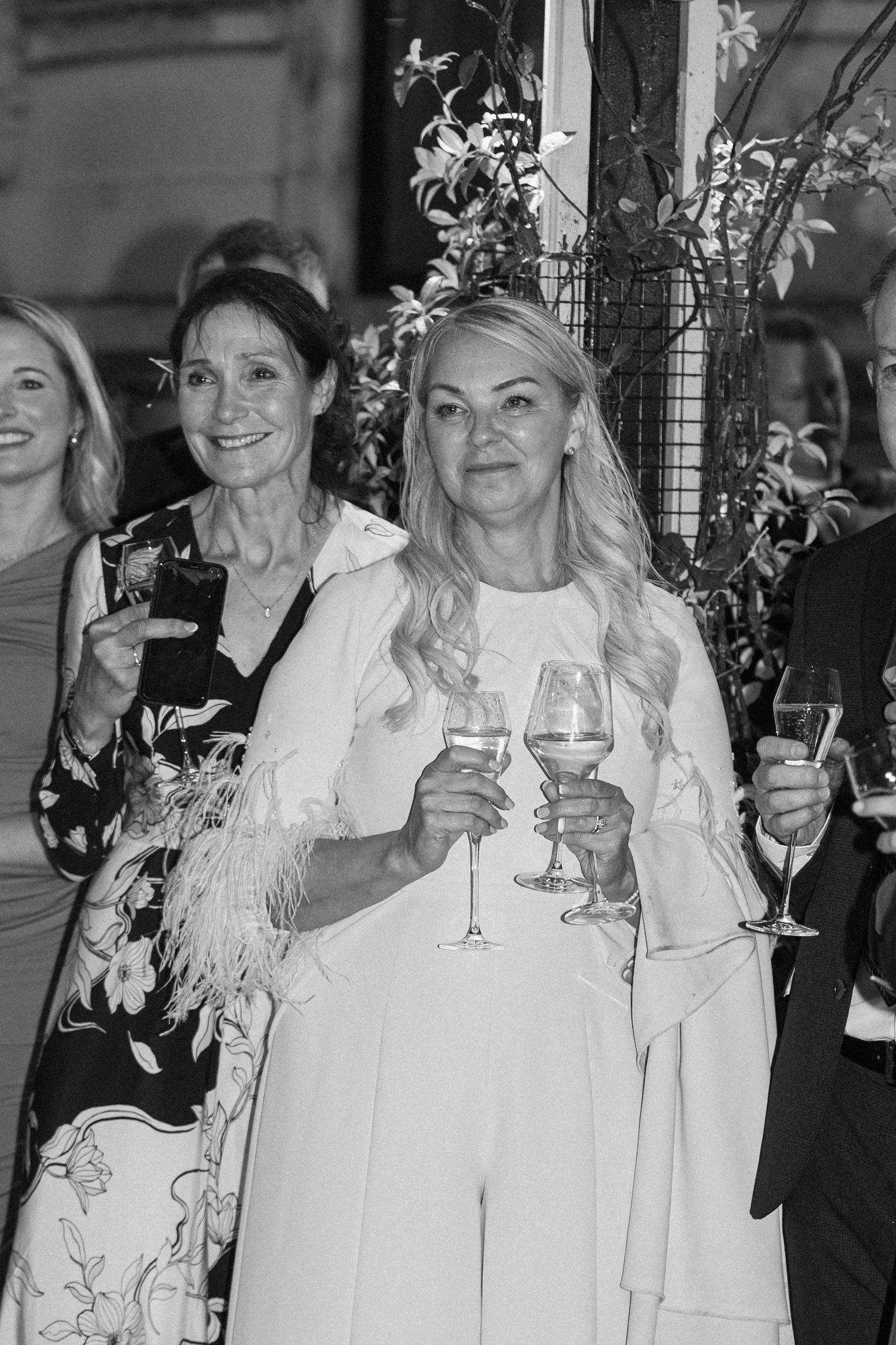 Wedding guests in formal attire raising champagne glasses for a toast.