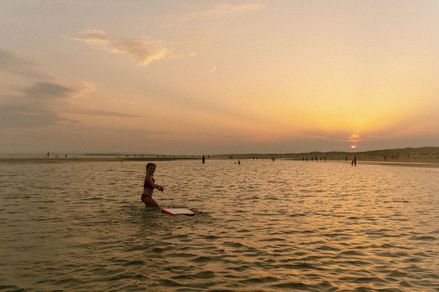 Silhouette of a paddleboarder gliding across calm waters during a golden sunset.