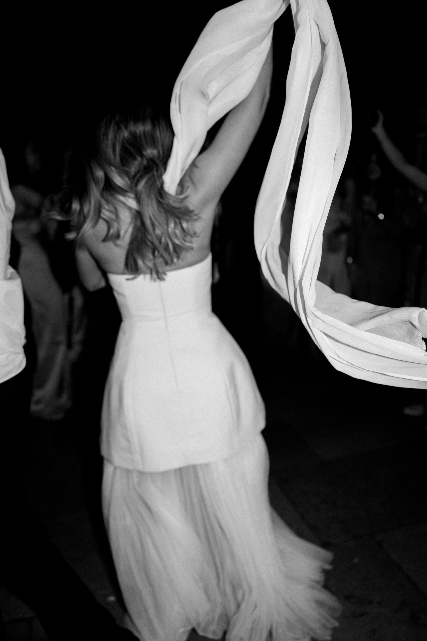Black and white photo of dancers in flowing white dresses at a celebration.