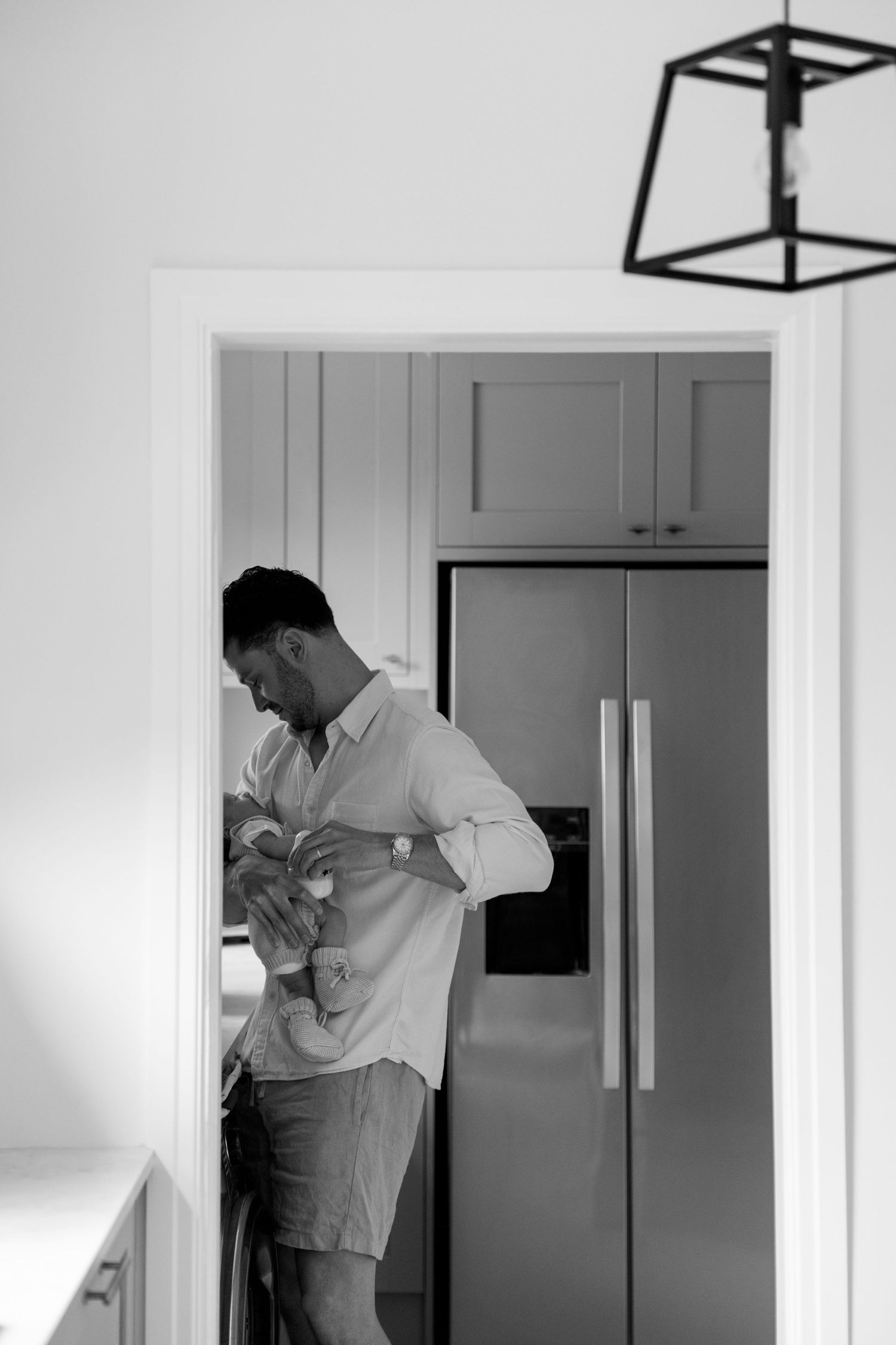 Series of black and white photos showing person in white shirt in modern kitchen.