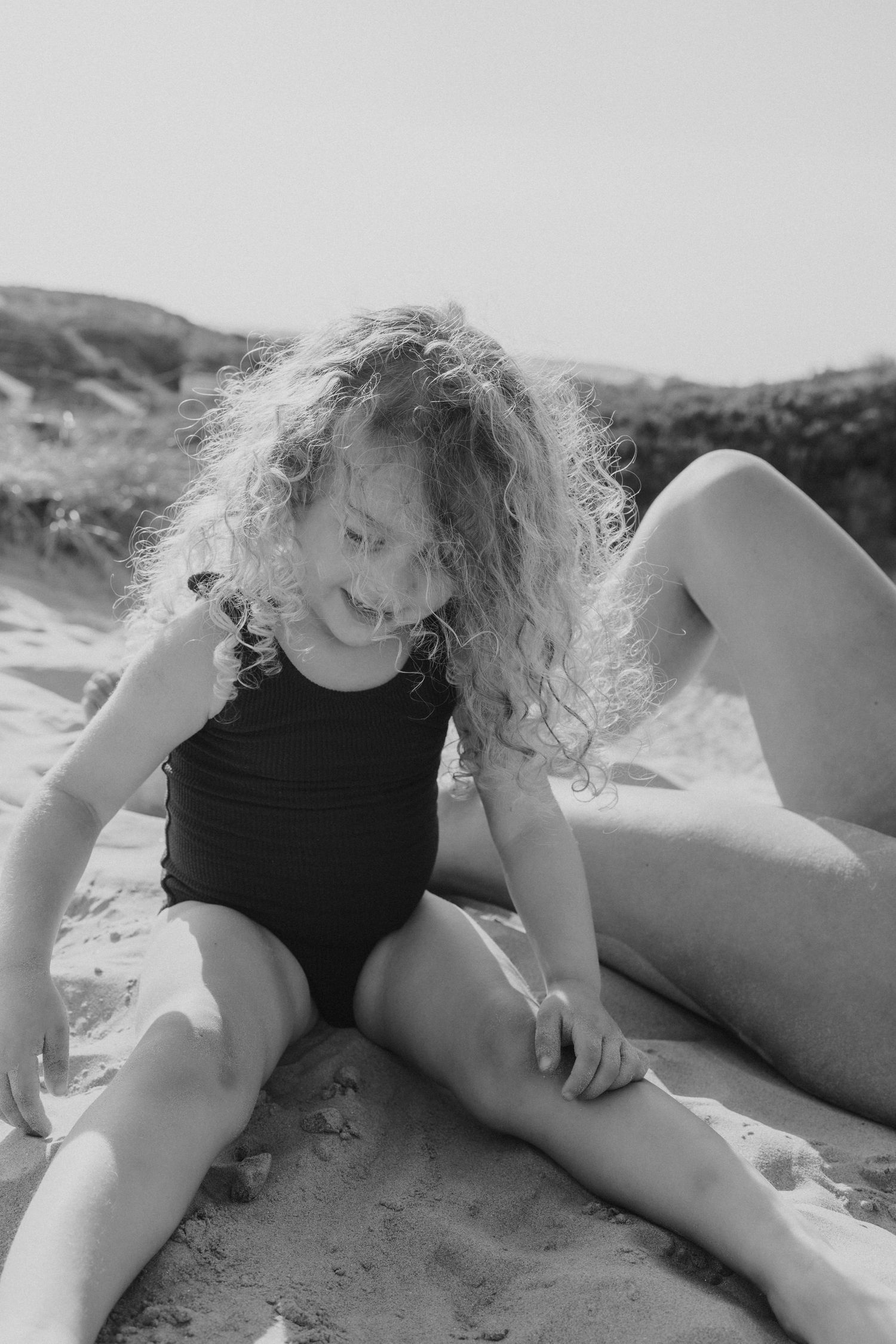 Black and white photo of people relaxing on beach sand.