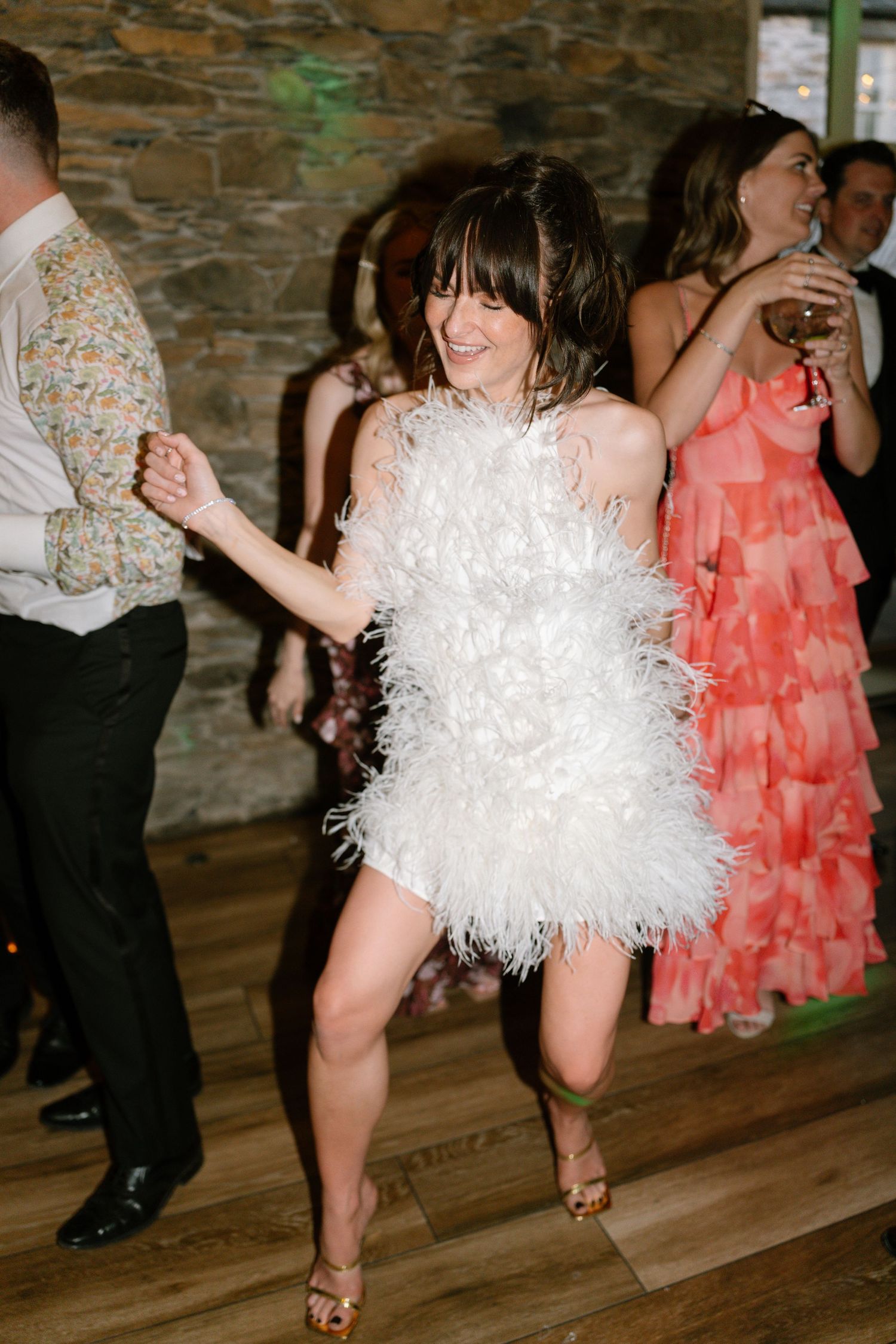 Wedding reception dancers performing energetic moves in a rustic venue with stone walls.