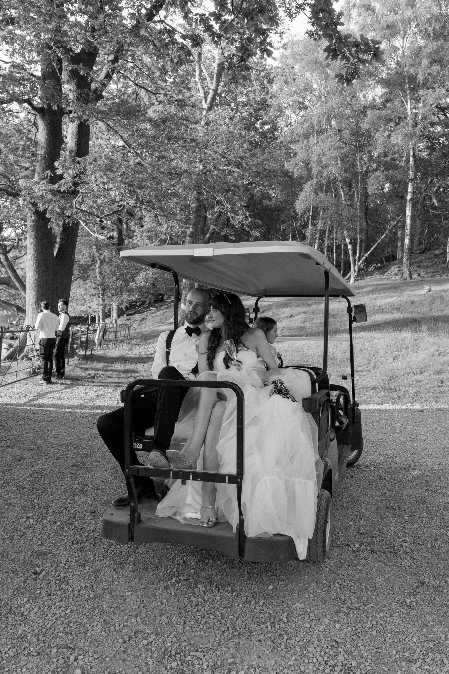 A golf cart transports wedding party members across a grassy landscape.