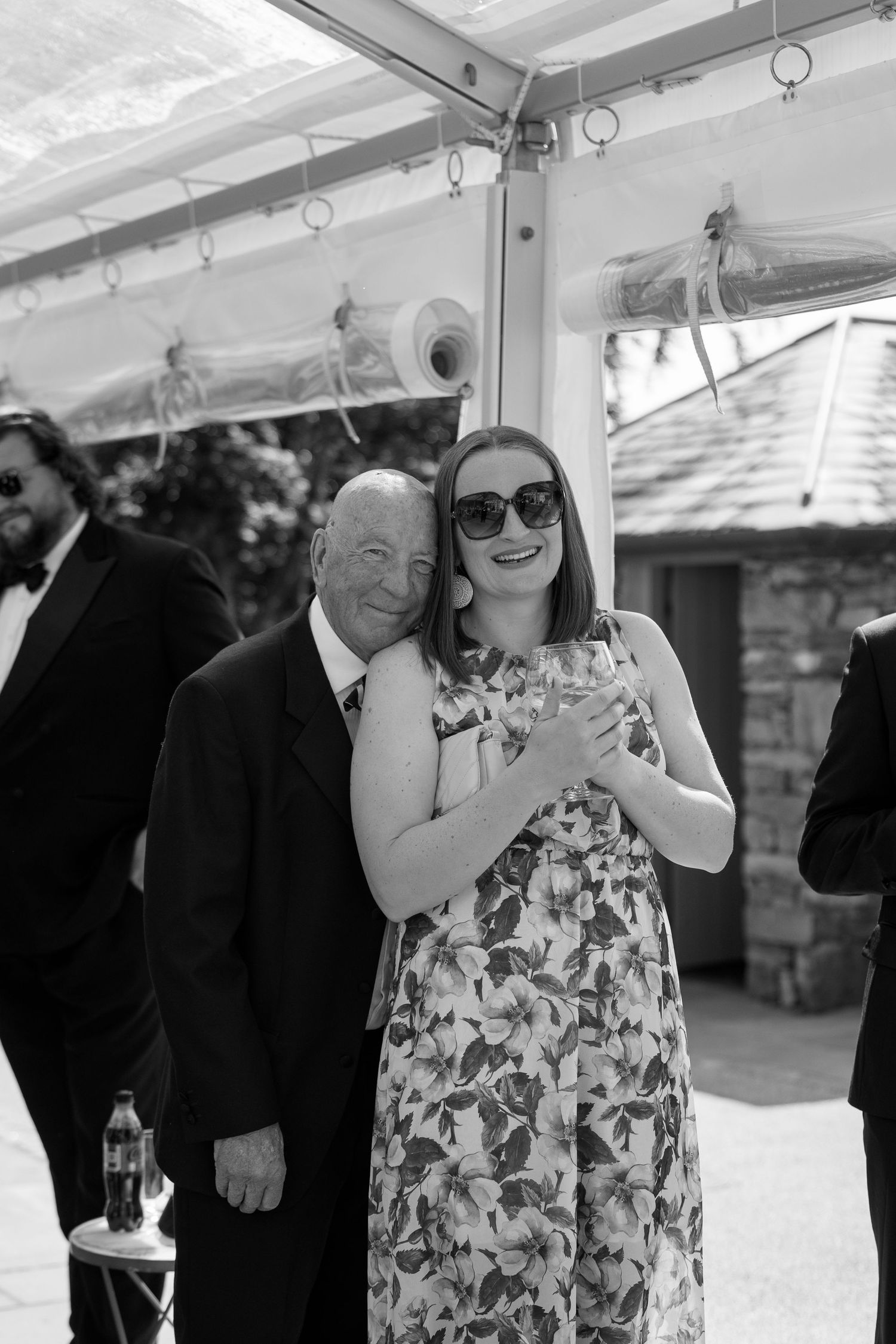 Wedding guests enjoying outdoor reception under clear tent.