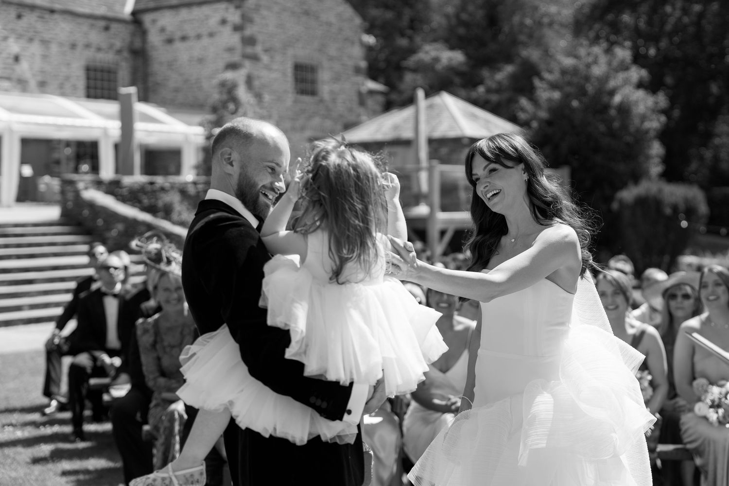 Wedding party dancing and celebrating in black and white on an outdoor patio.