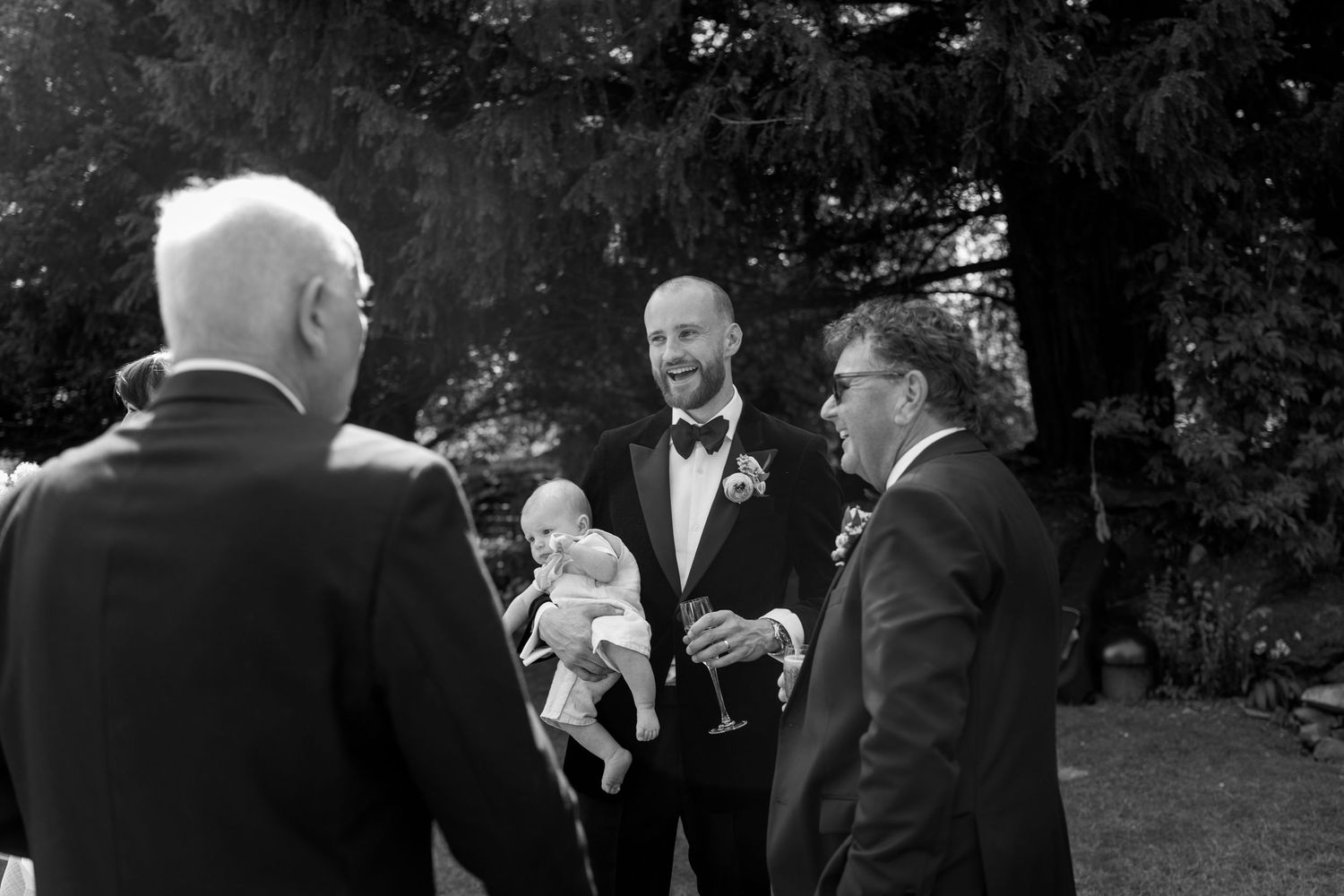 Guests in formal attire converse during an outdoor wedding reception.