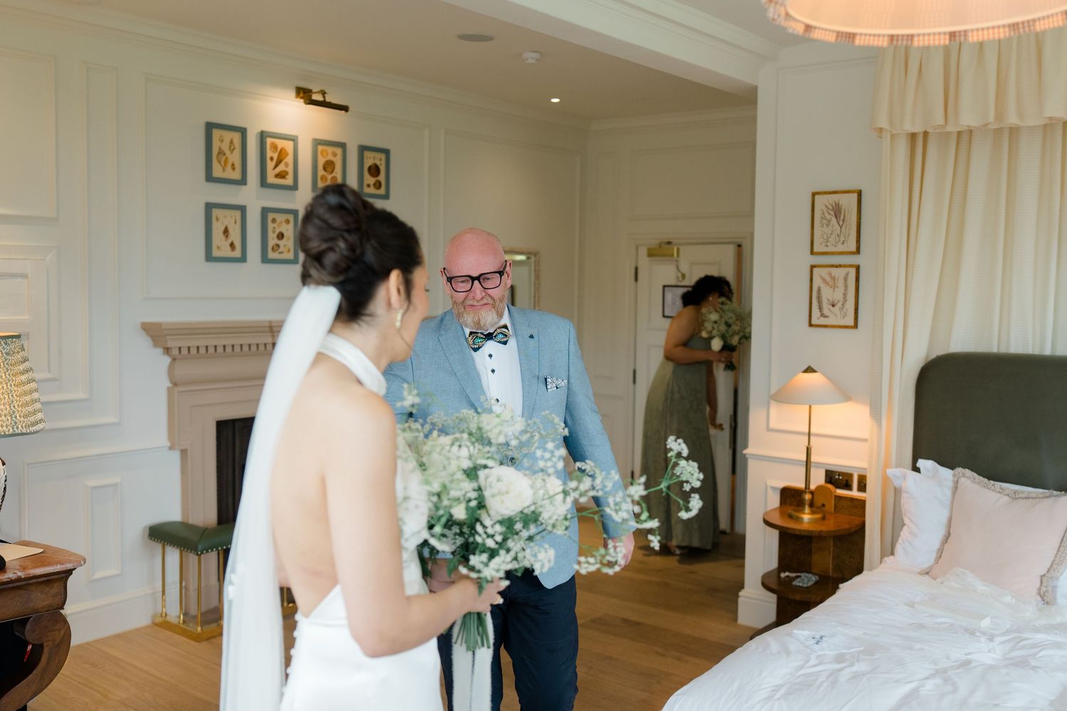 Emotional father holding flowers reacting to seeing his daughter in her wedding dress.