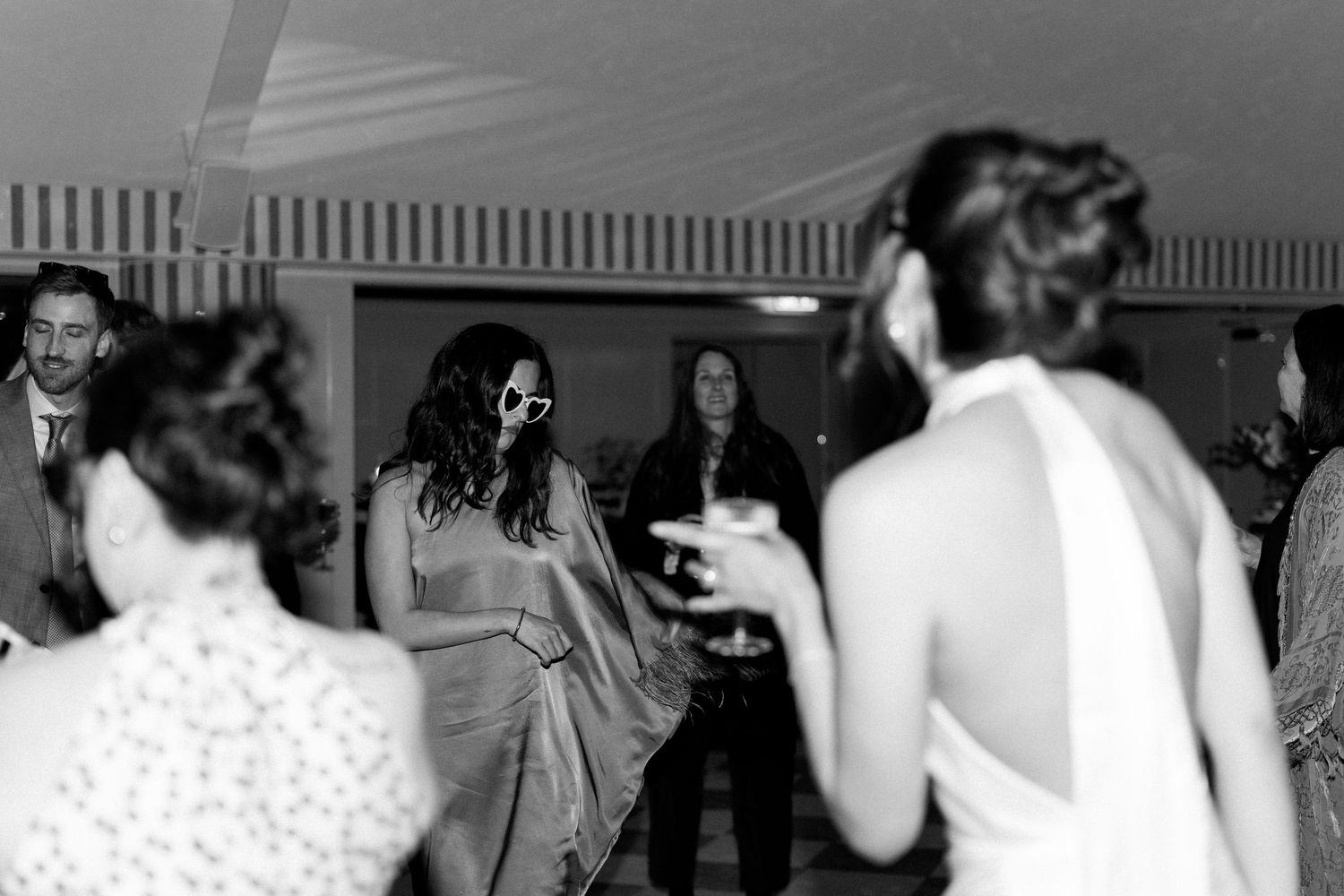 Bride dances with guests including a woman in a saree at a lively wedding reception.
