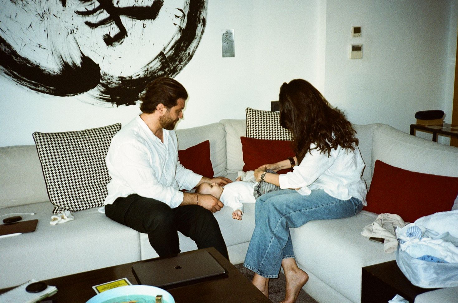 A man and woman sit together on a white sofa in a modern living room, sharing an intimate moment.