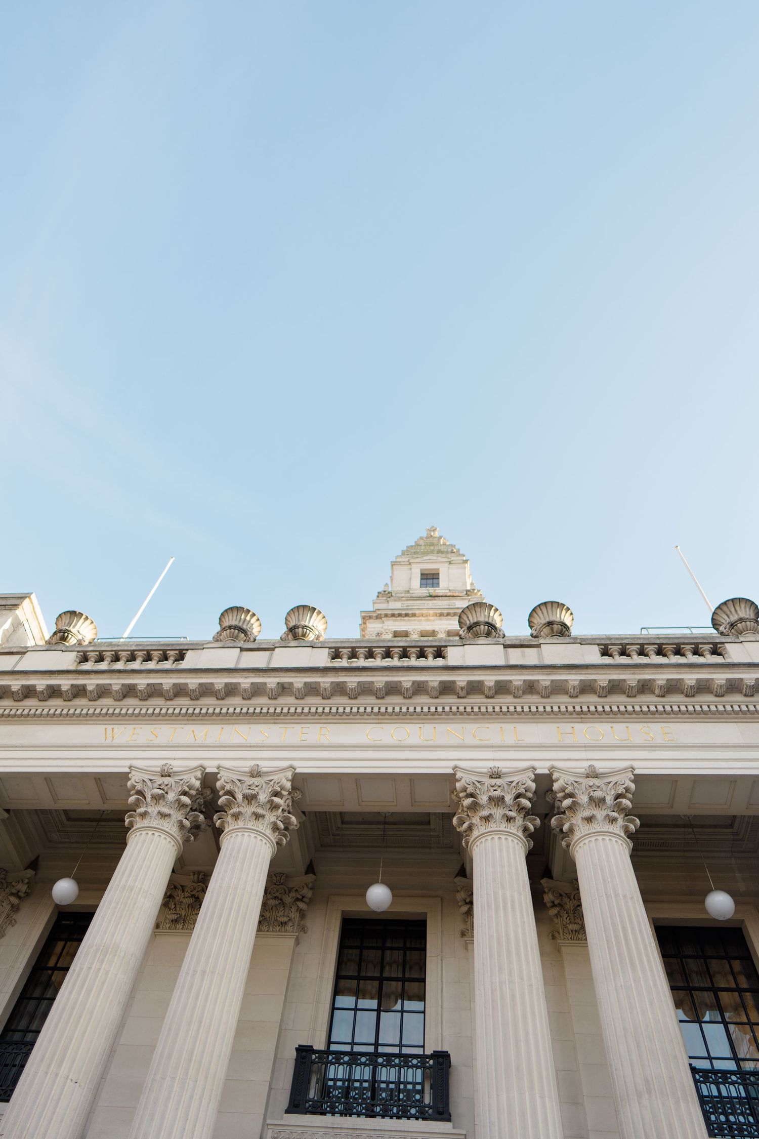 Classical white stone building facade with Corinthian columns against blue sky.