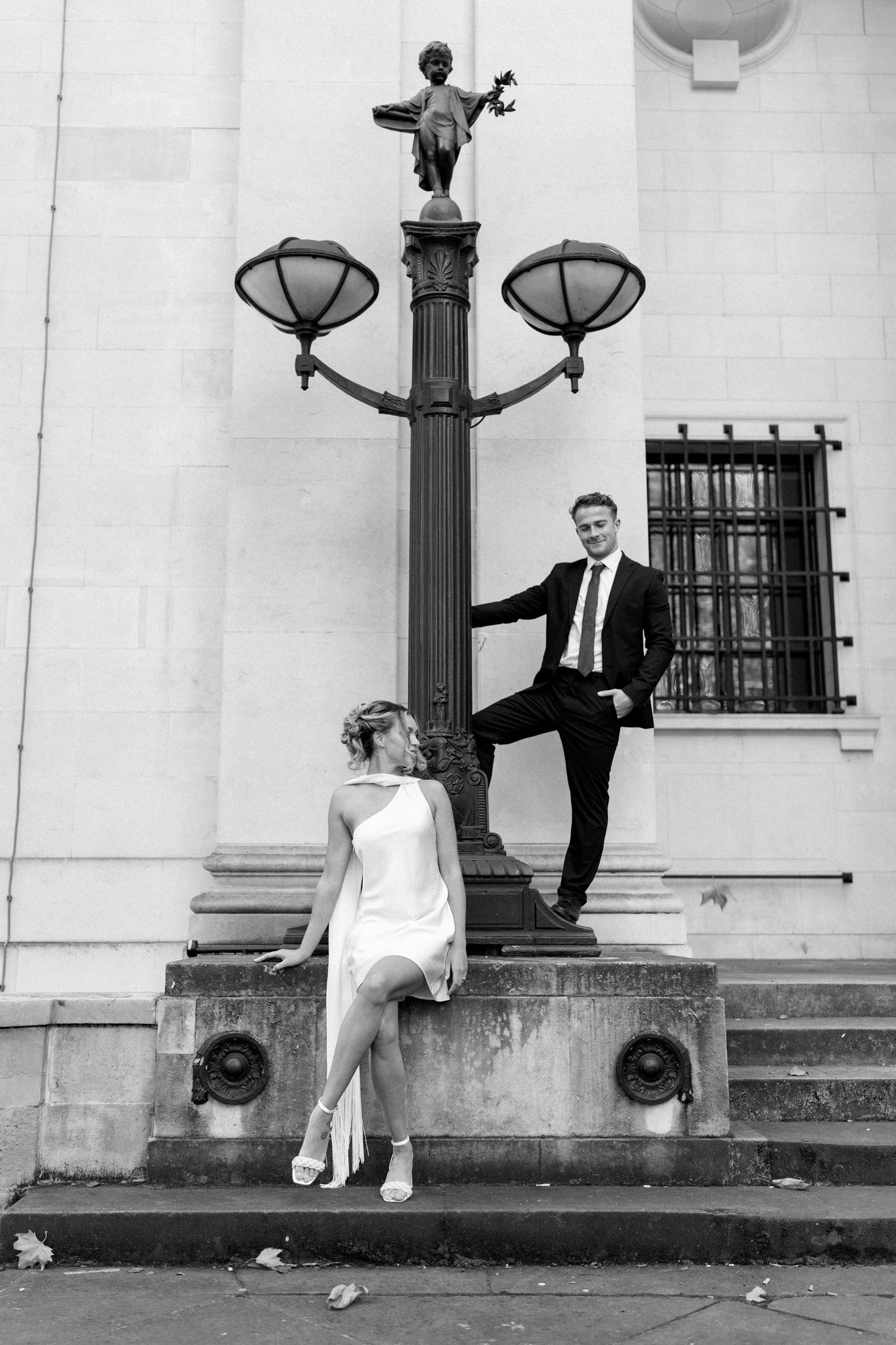 Black and white photos of a couple posing by ornate lamp posts.