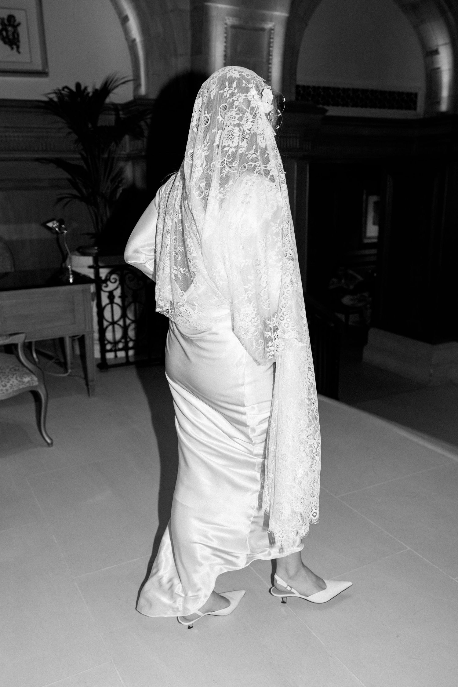 Black and white images of white wedding dresses with lace details on a light colored floor.