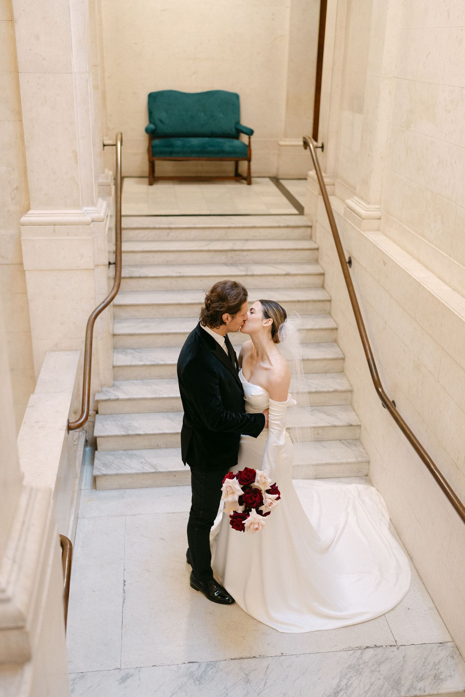 A wedding couple shares intimate moments on marble stairs with teal accents.