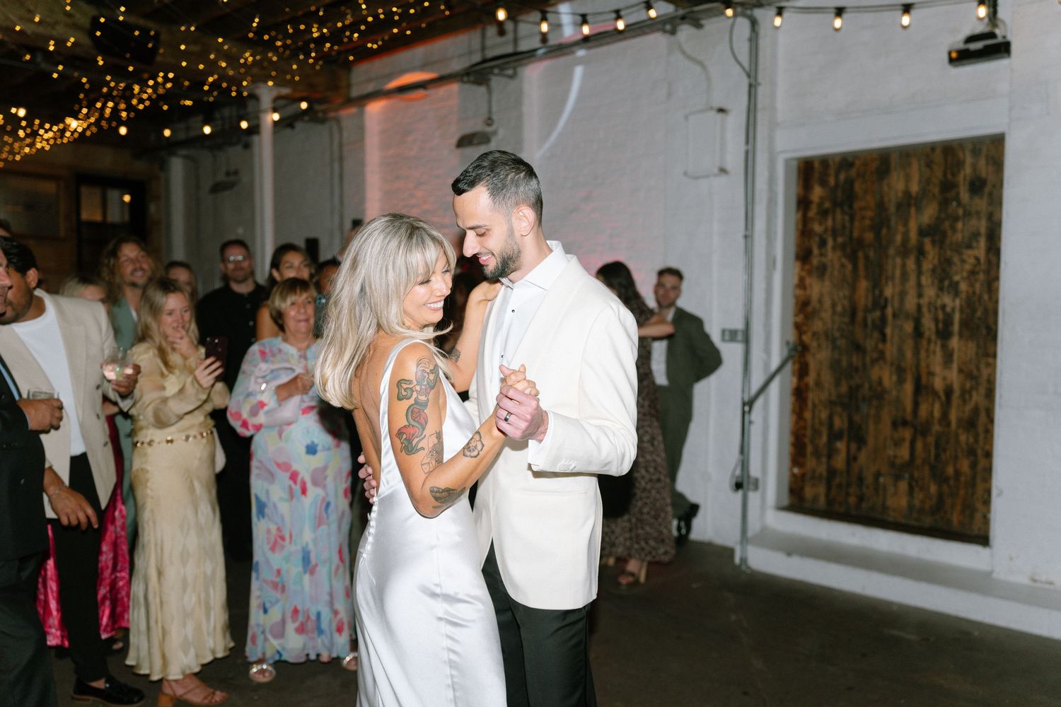 Wedding reception dance floor under string lights in an indoor venue.
