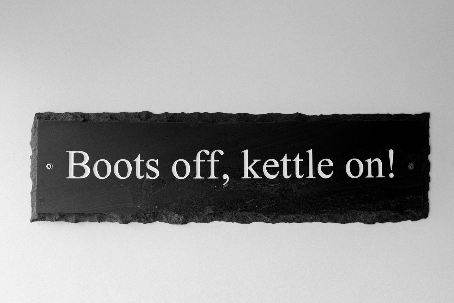 A black and white text image displaying the phrase 'Boots off, kettle on!' in a simple font against a dark background.