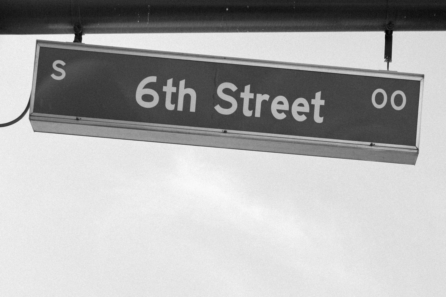 Street sign showing 6th Street against a light background.