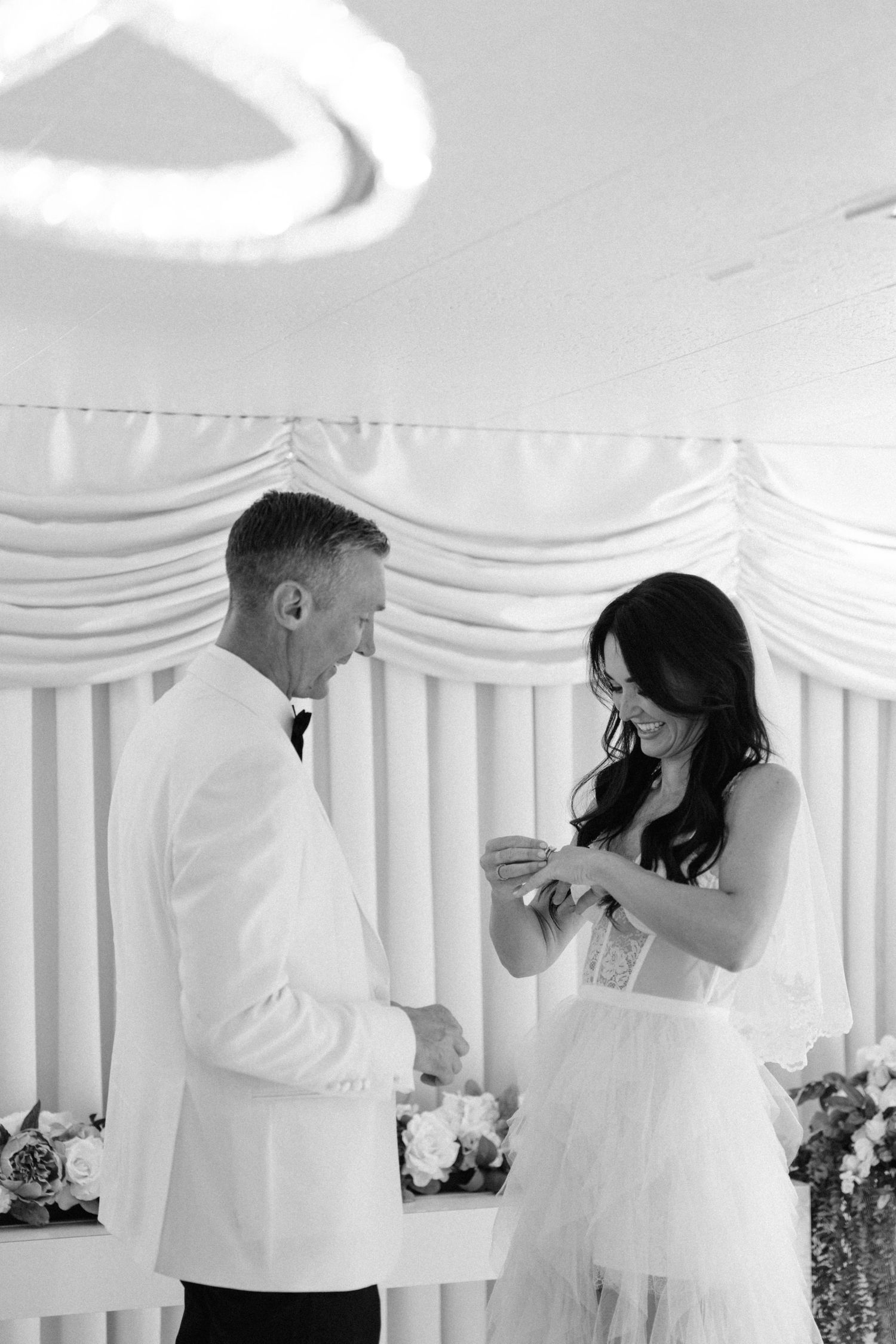 Couple sharing an emotional moment during their wedding ceremony in a white-decorated chapel.