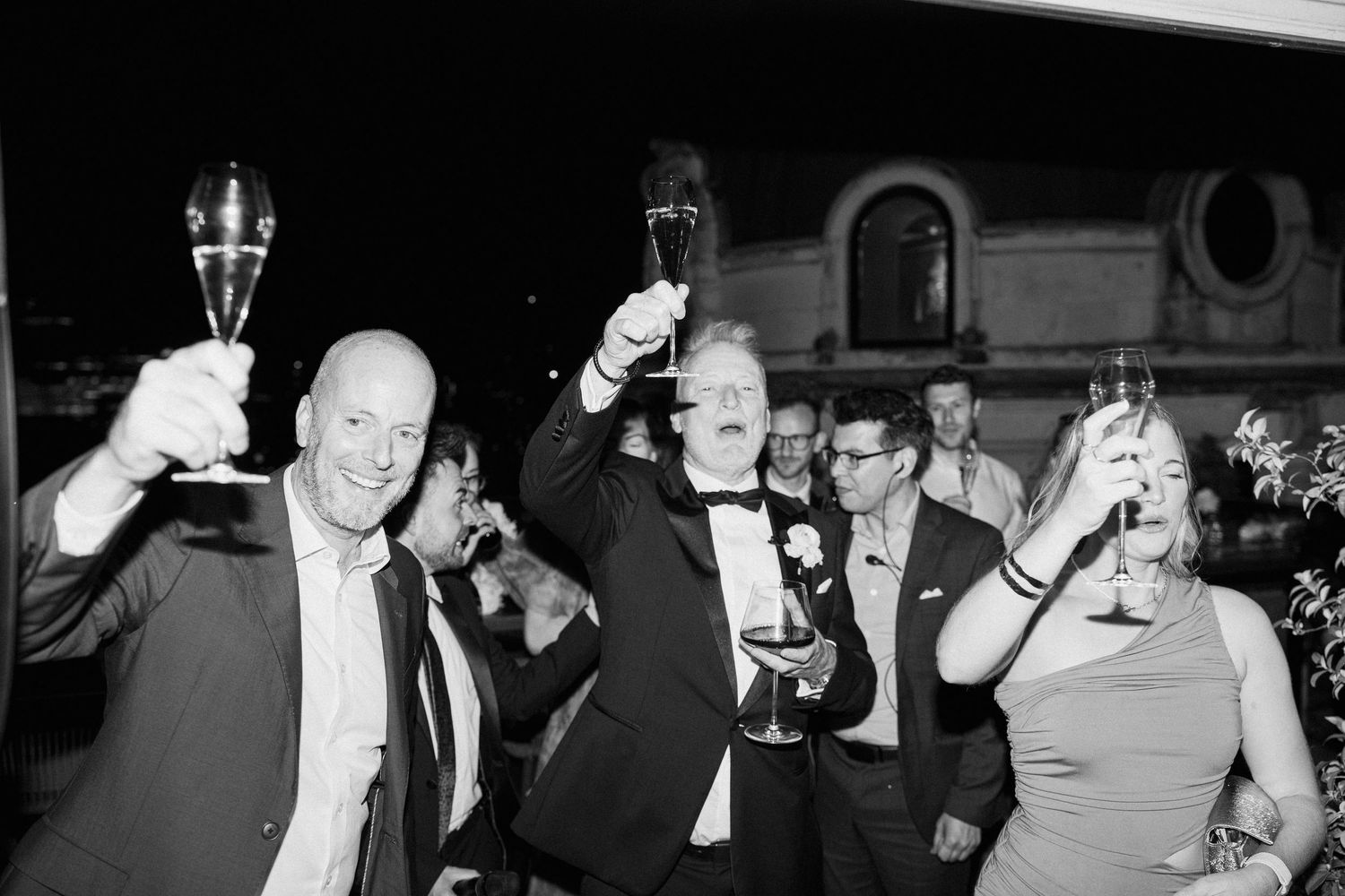 Wedding guests raising glasses in celebration during a reception.