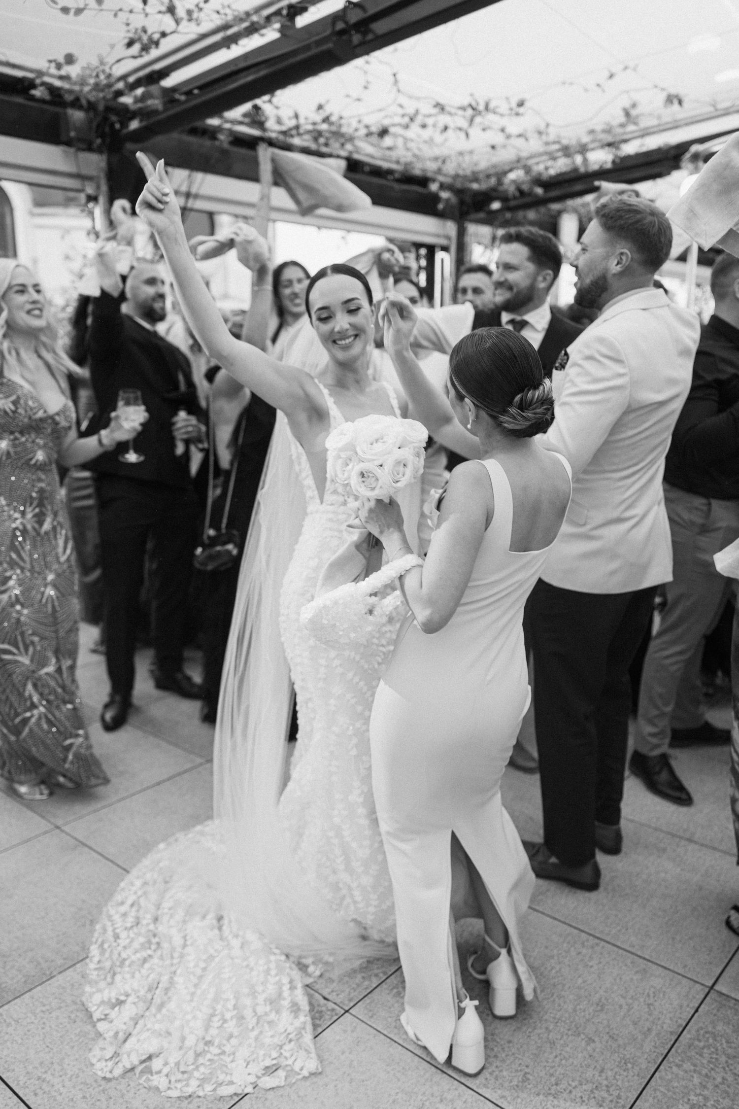 Wedding guests dance and celebrate together at an indoor reception venue.