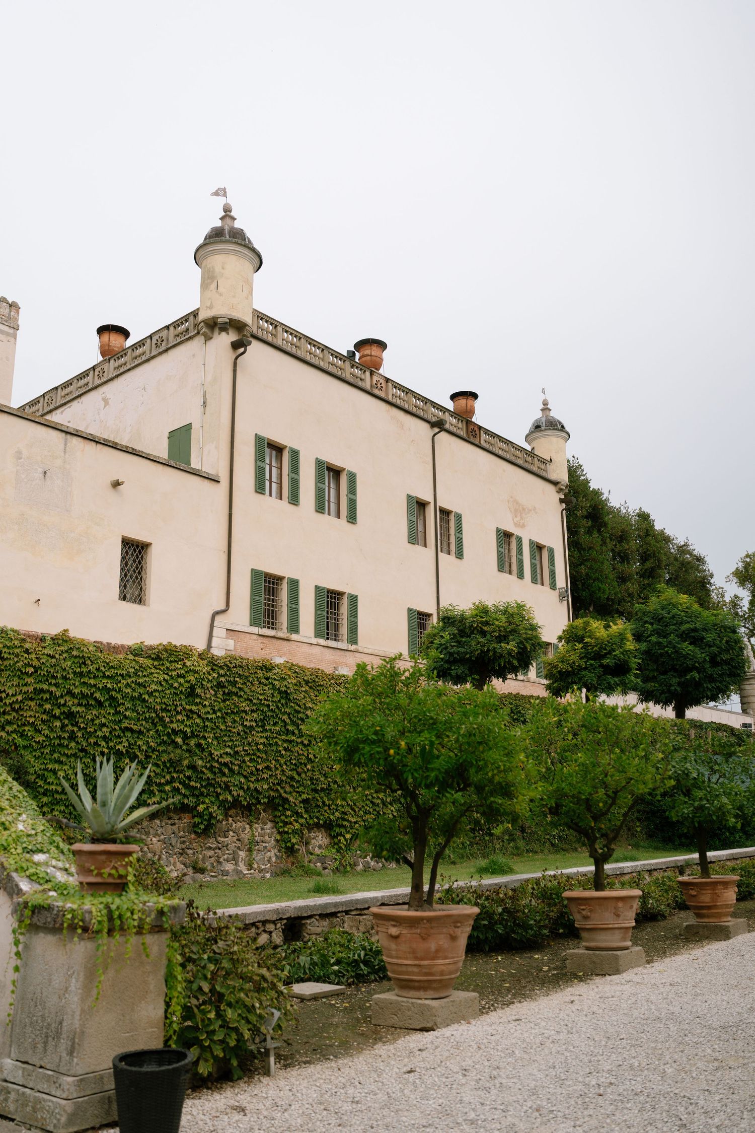 Historic Italian villa with green shutters and ivy-covered walls stands on a hillside.