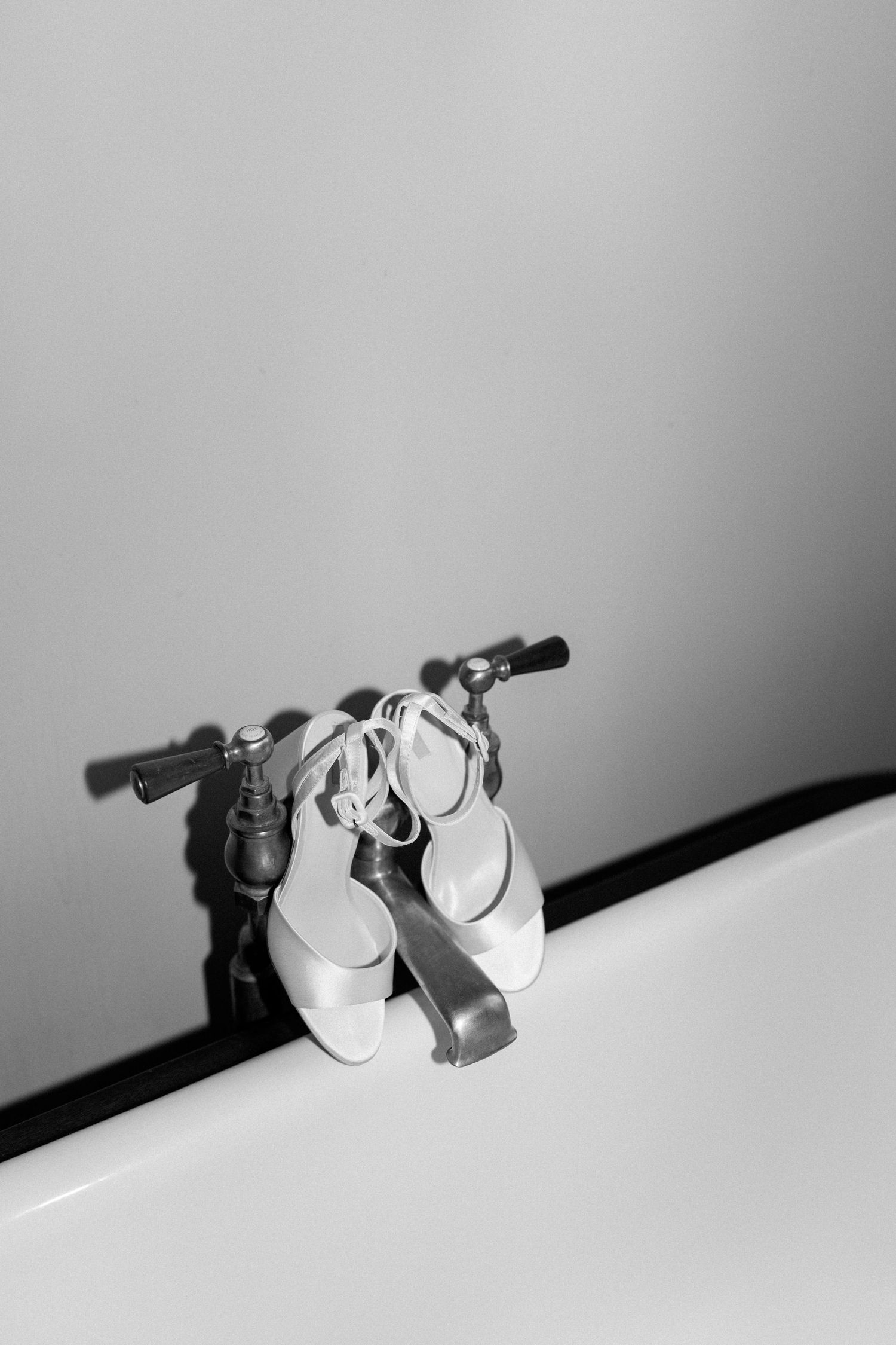 Dramatic shadow play of white bridal shoes reflected against a light wall.