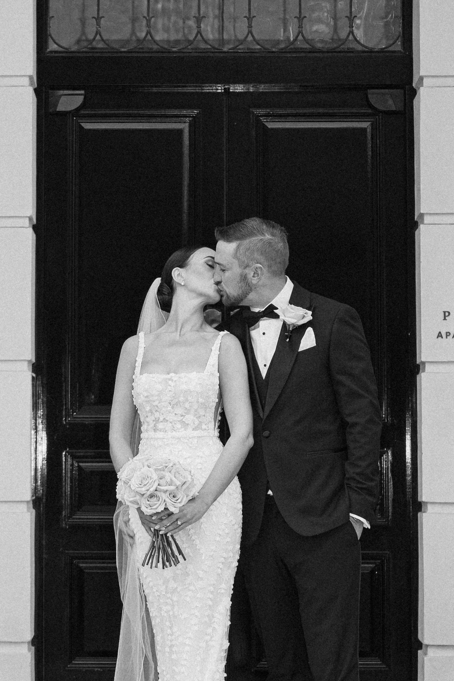 Intimate black and white moment of newlyweds by classic doorway.