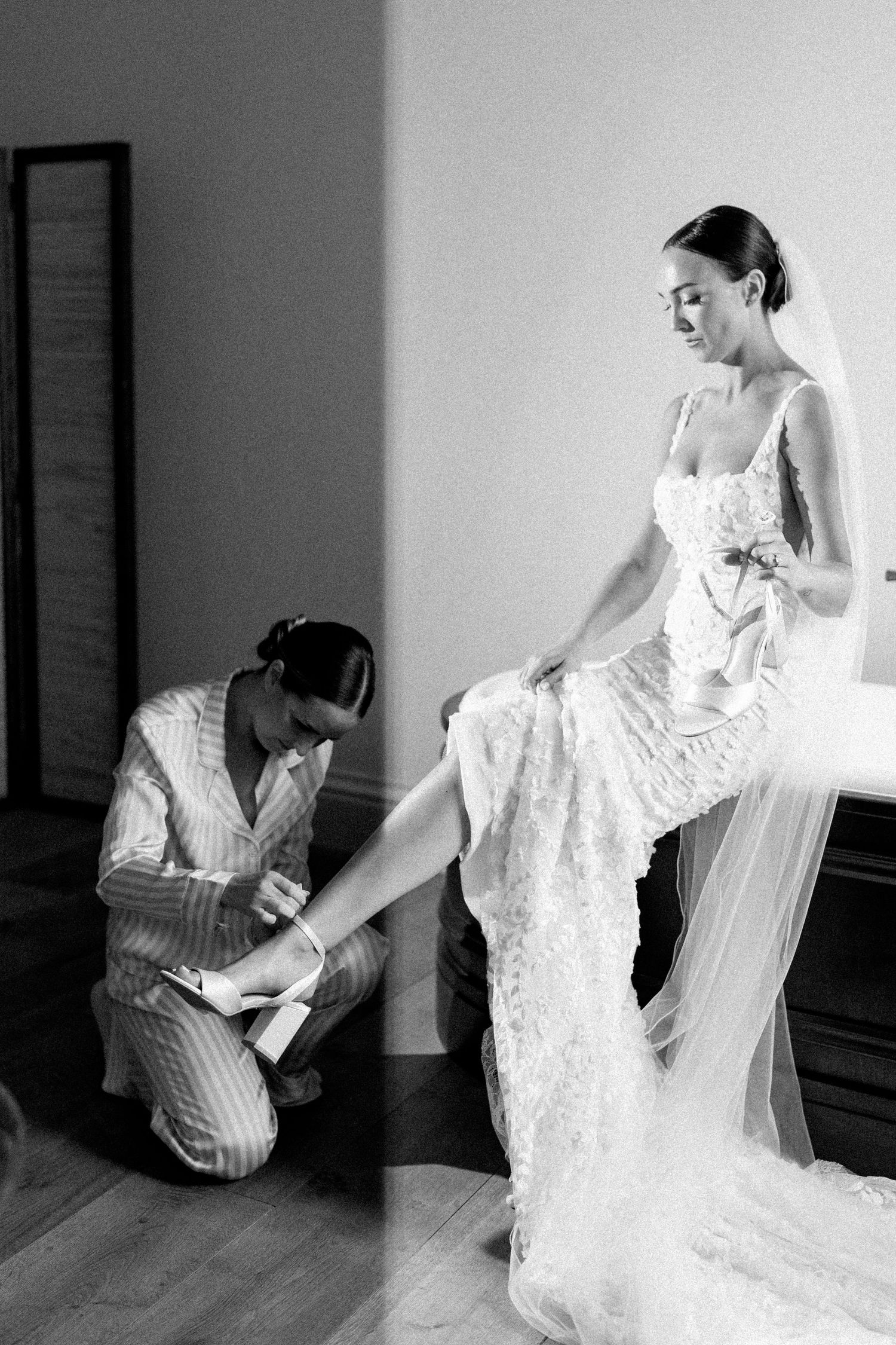 Artistic black and white photo series showing a bride in a lace dress getting ready in an elegant room.