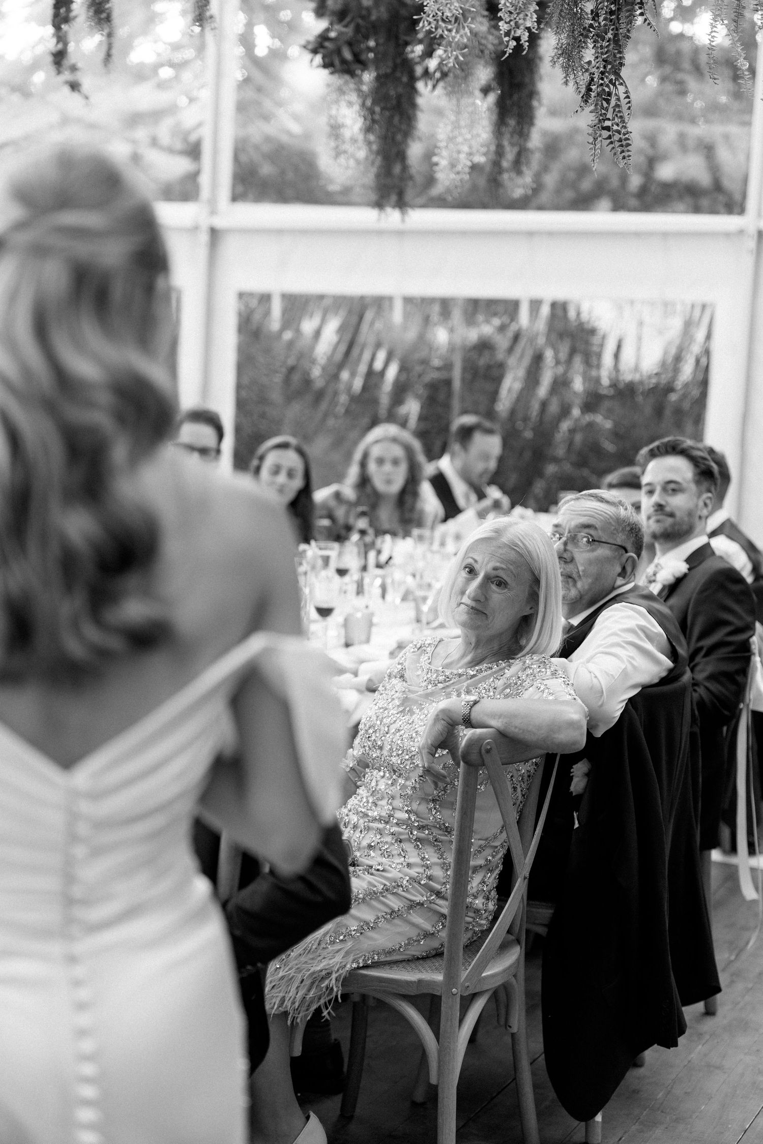 Black and white photo of guests enjoying a wedding reception under a tent.